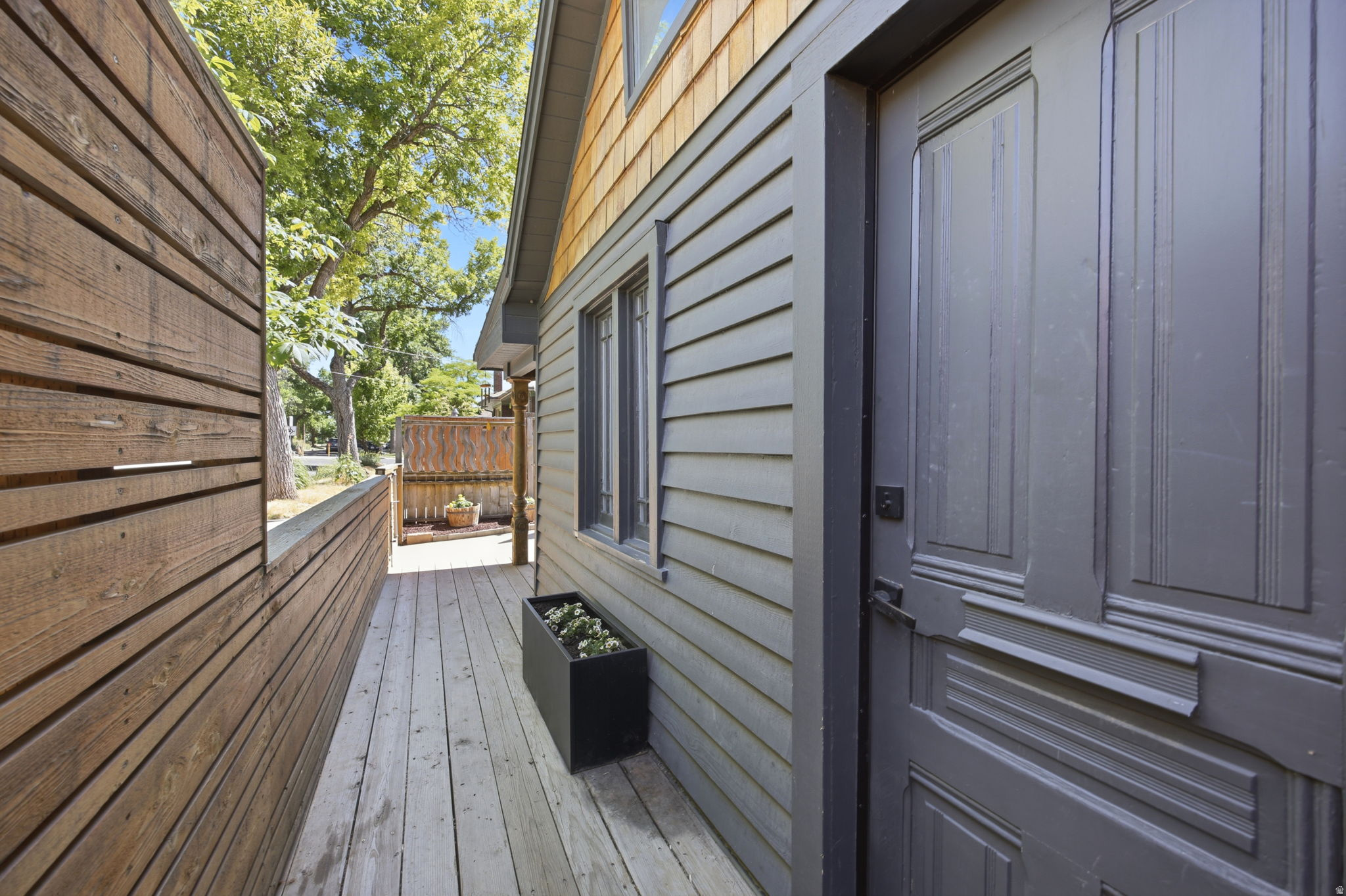 Outdoor deck featuring composite decking, horizontal wood fencing, and a dark paneled door