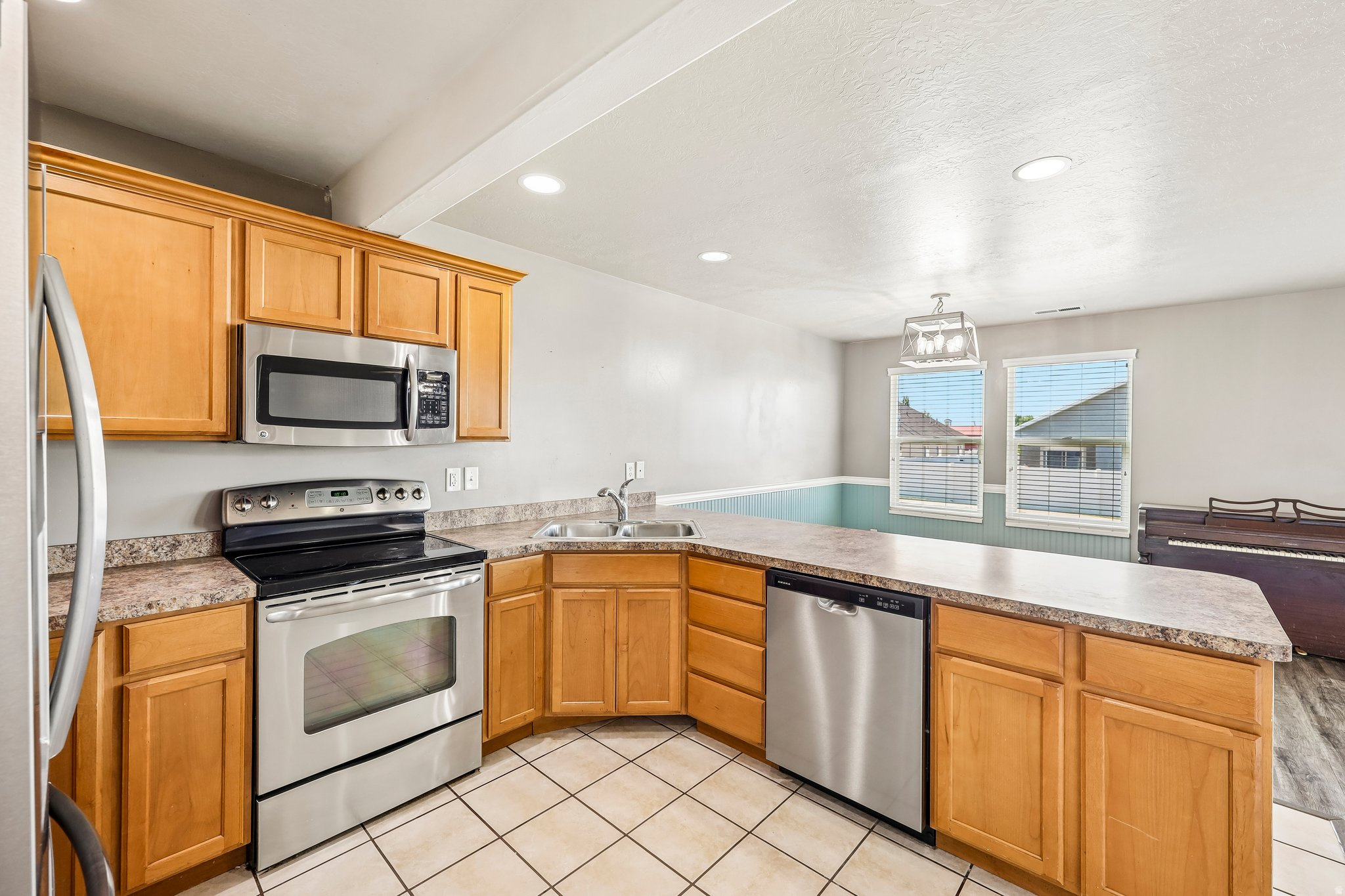 Kitchen featuring wood cabinetry, stainless steel appliances, speckled countertops, and tile flooring