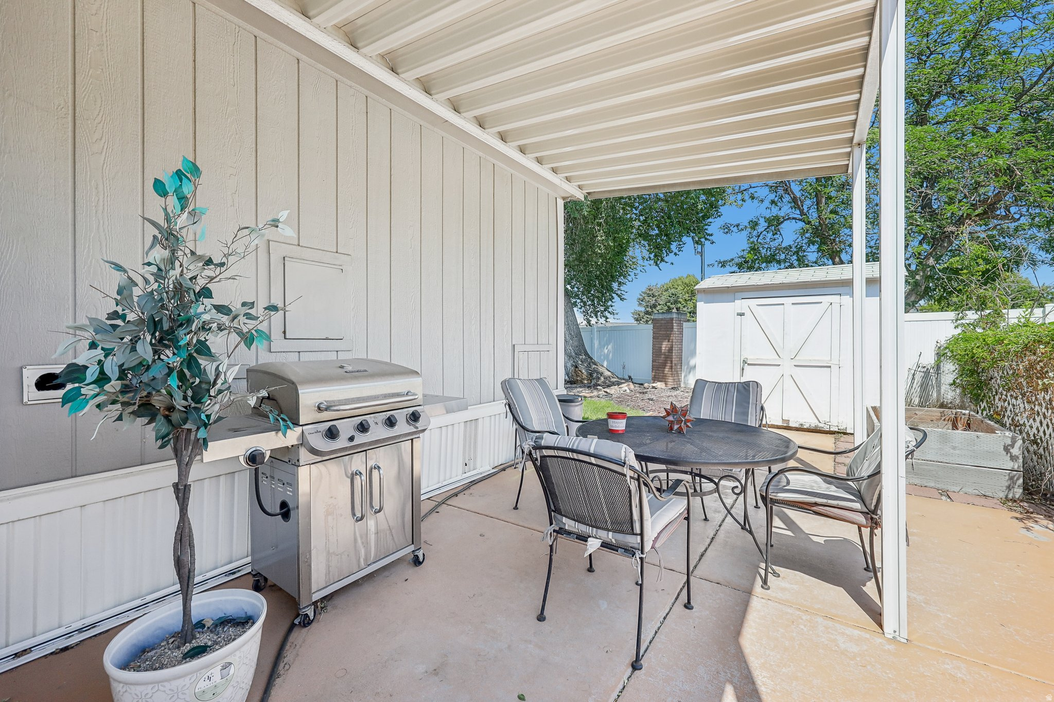 Covered patio area featuring a concrete slab and a white privacy fence