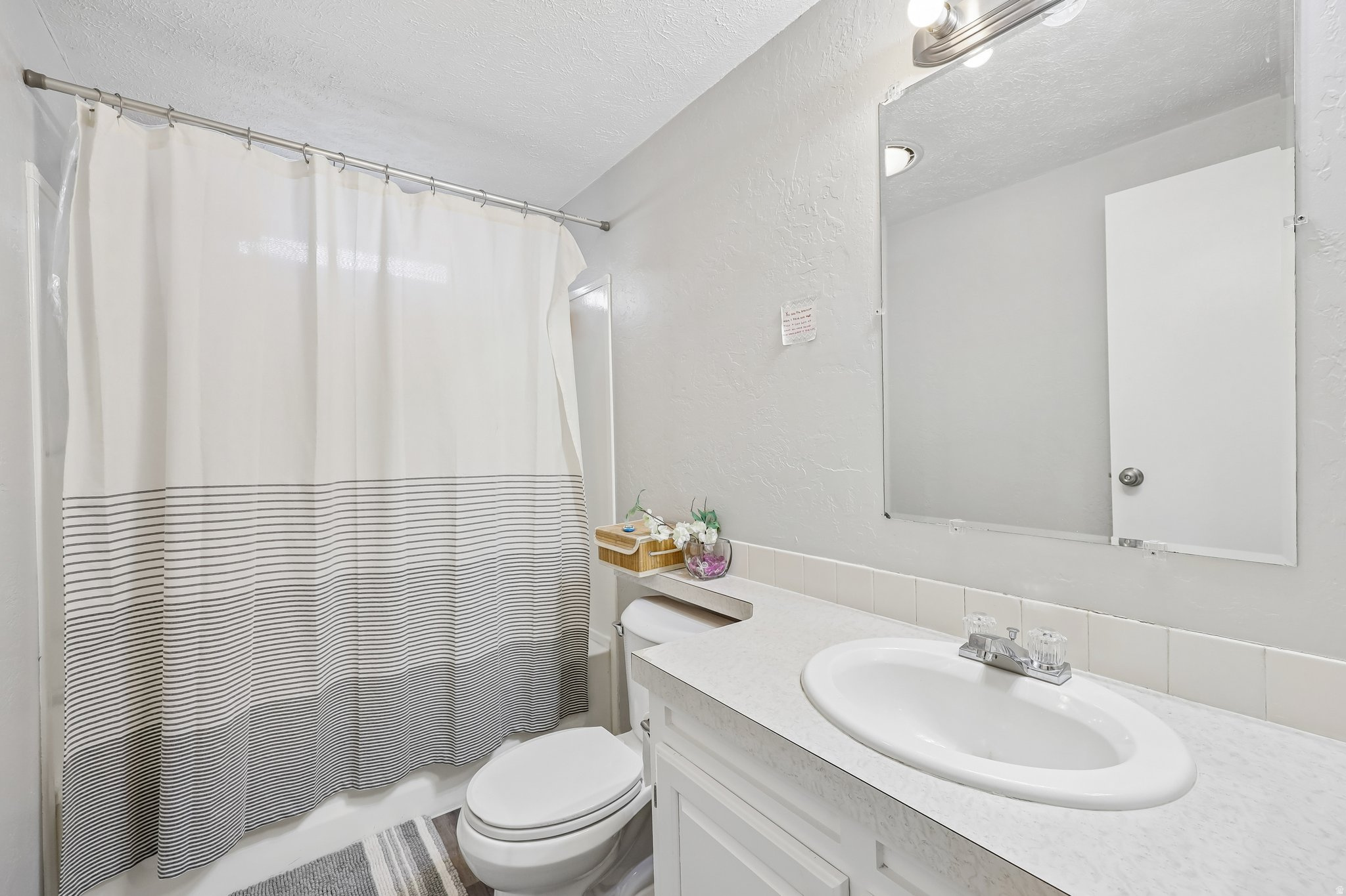 Bathroom featuring a full-size vanity with an integrated sink, a wall-mounted mirror, and a tub/shower combination