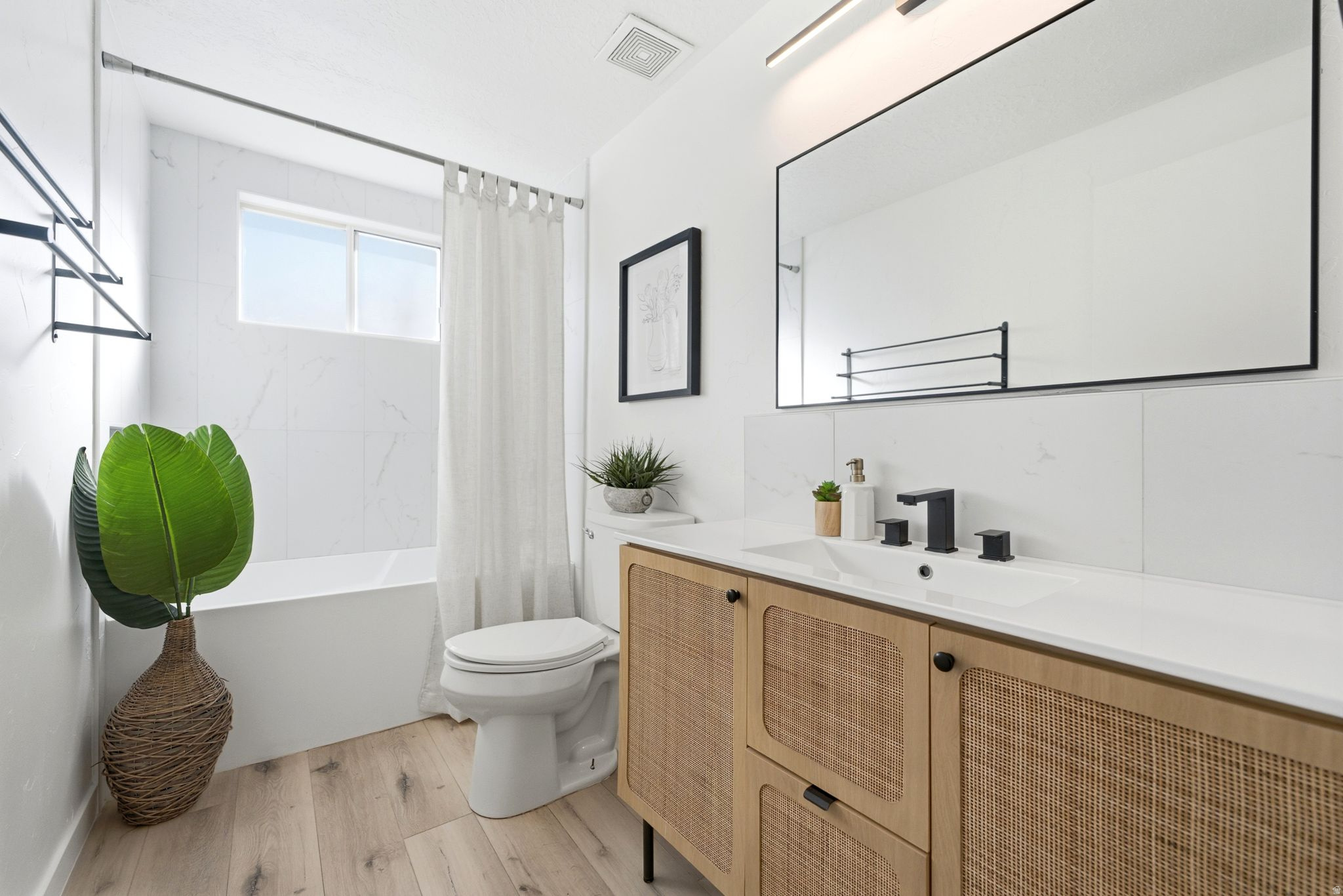 Modern bathroom featuring a wood-finish vanity with woven paneling, integrated sink, and matte black faucet