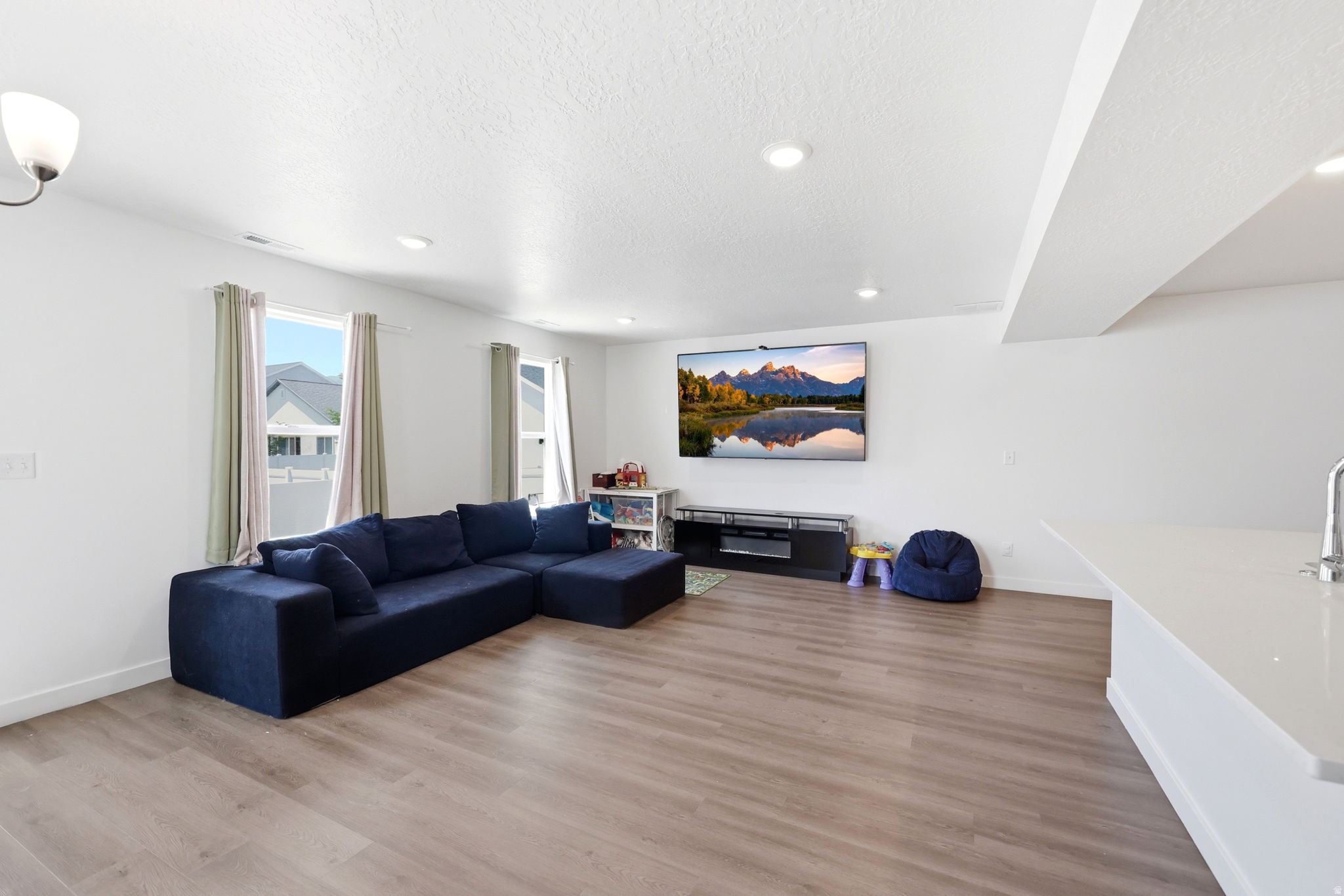 Open living space featuring wood-finish flooring and recessed lighting