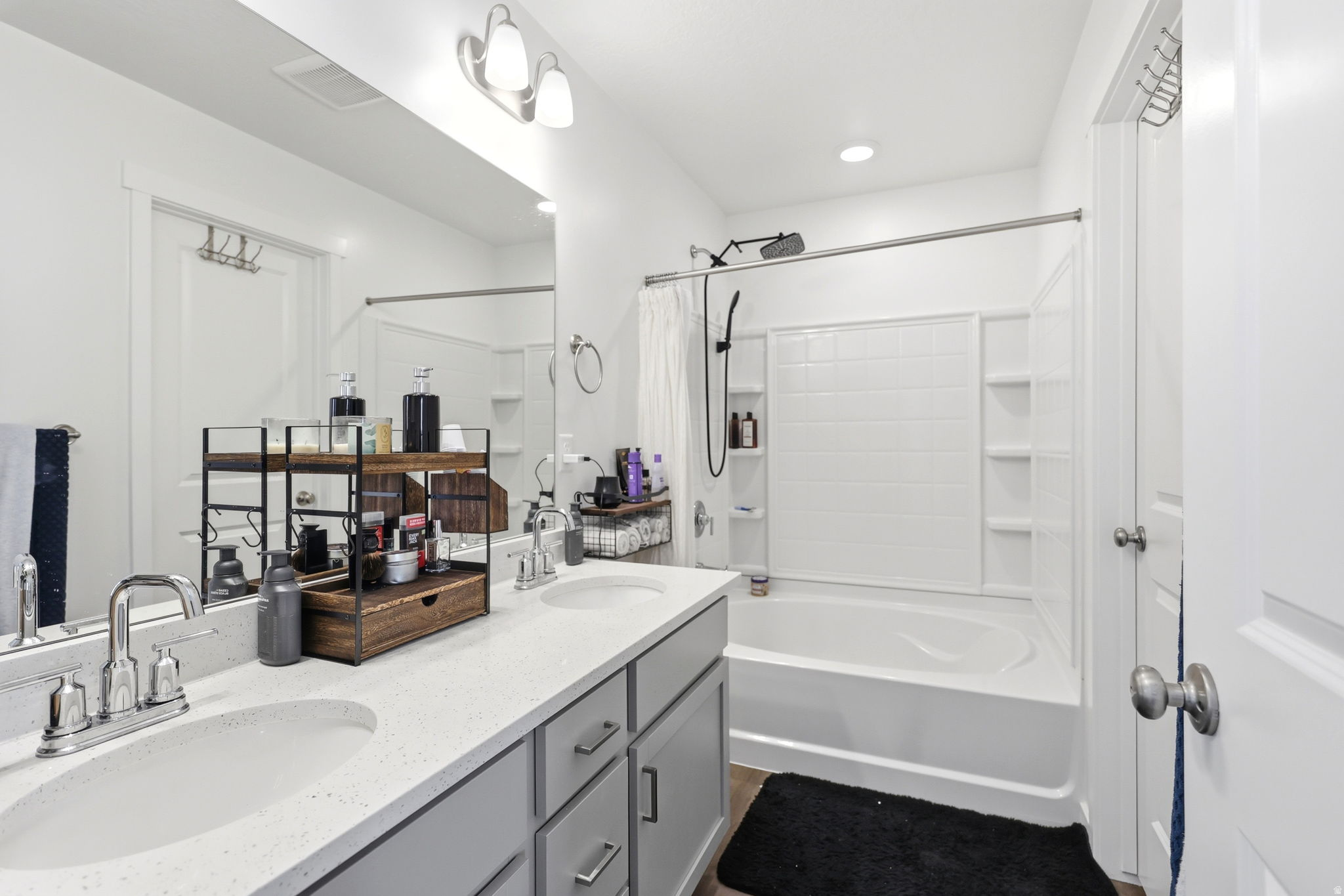 Bathroom featuring a double vanity with stone-finish countertops, undermount sinks, and grey shaker-style cabinetry