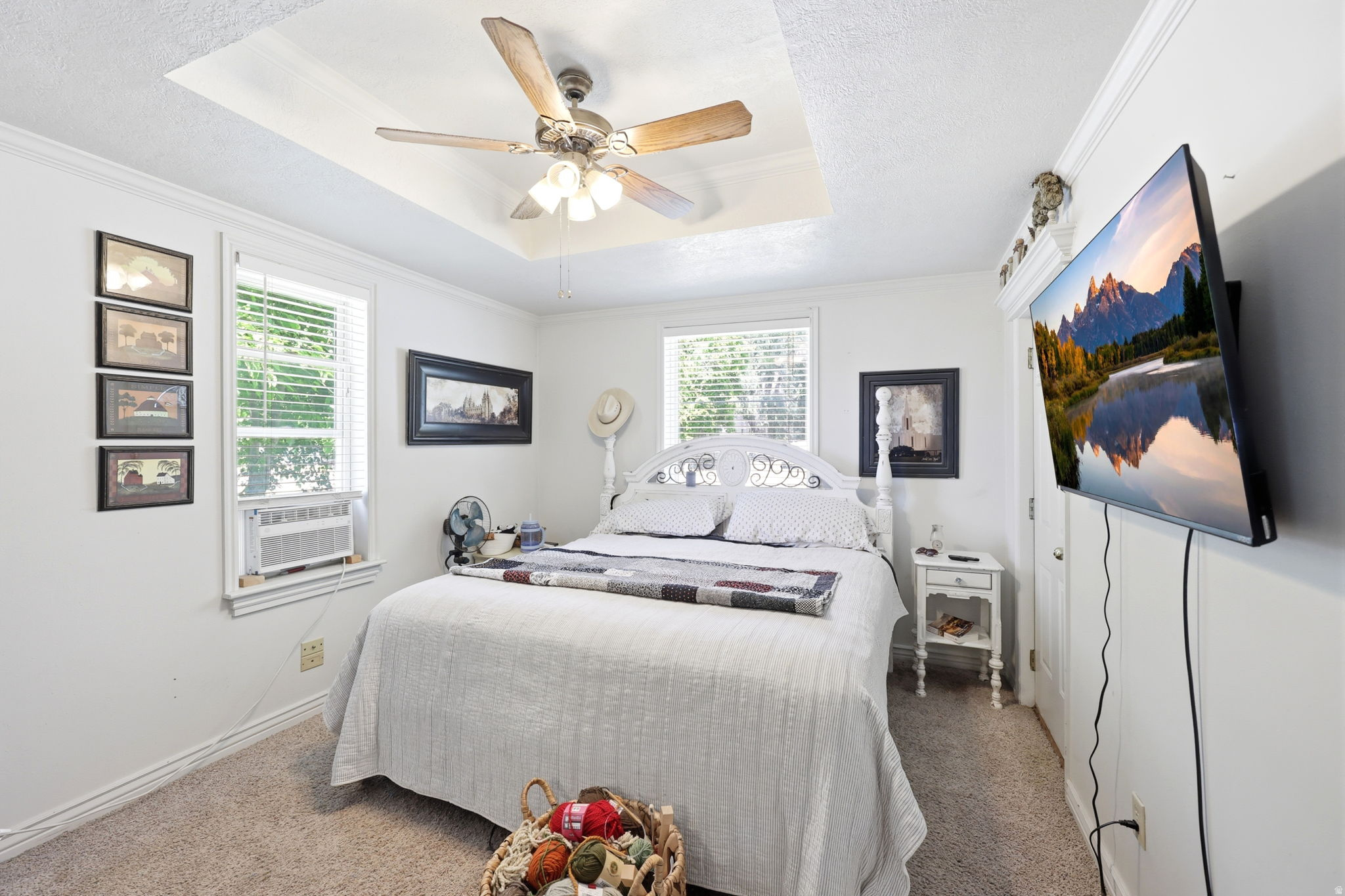 Carpeted bedroom featuring a tray ceiling with a ceiling fan, white trim, and white walls