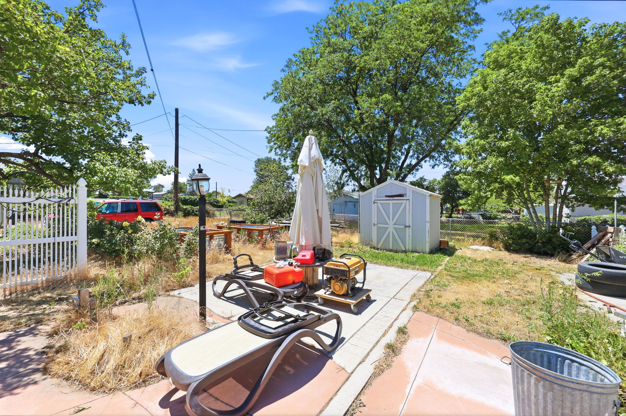 Rear yard featuring a concrete patio, a detached storage shed, and mature trees