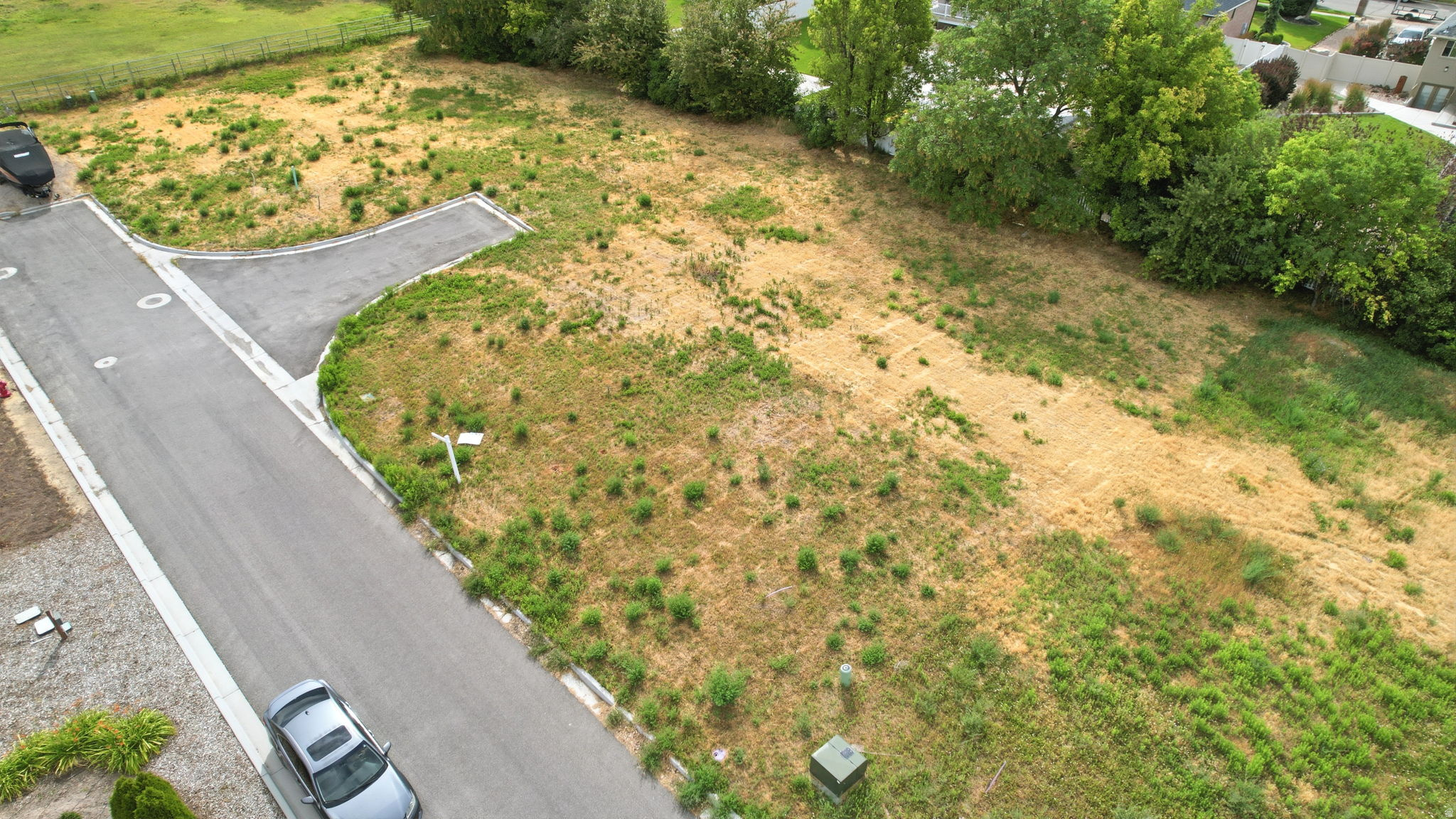 Expansive land parcel featuring established paved road access, designated utility connections, and mature perimeter trees