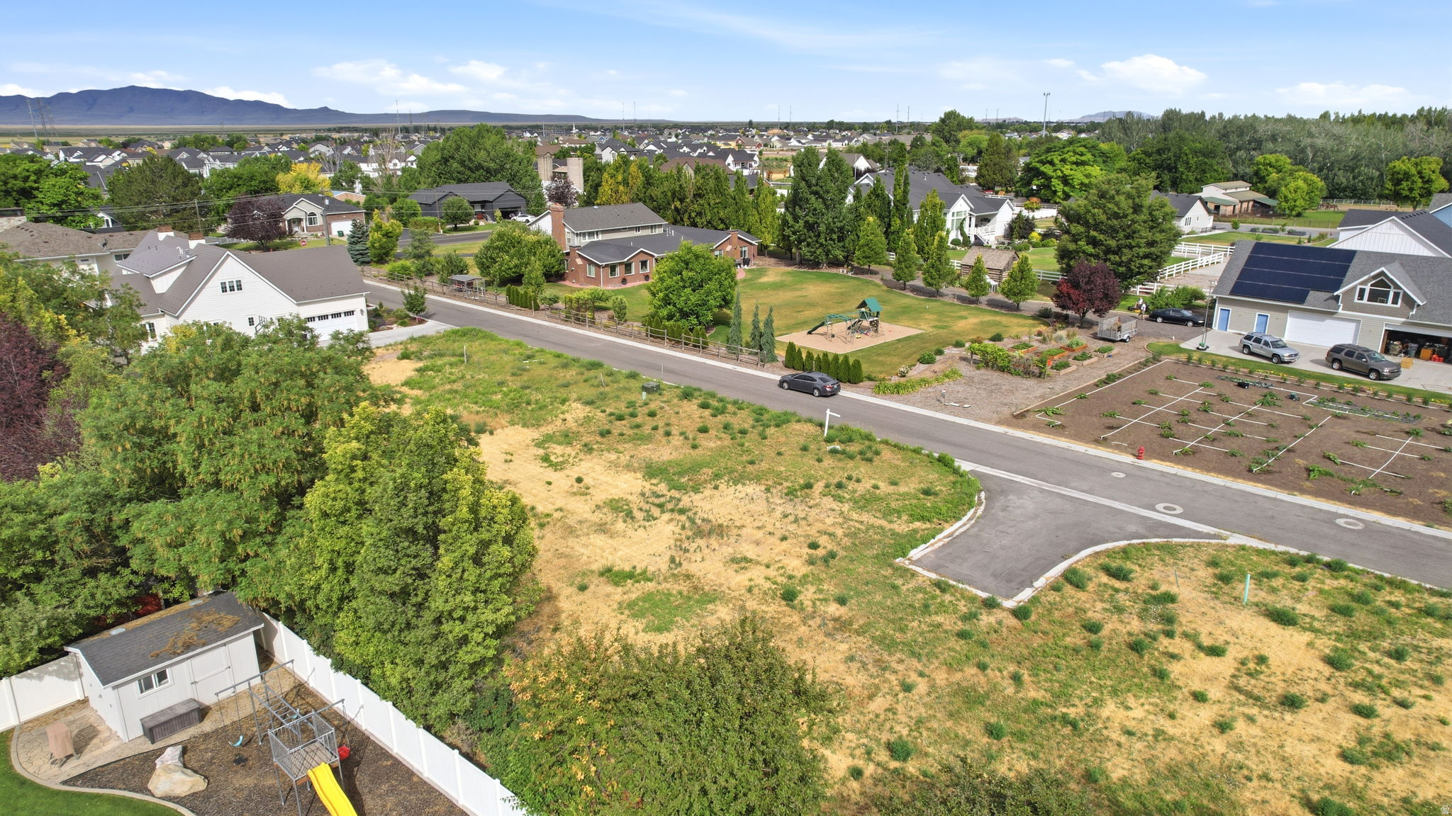 Expansive undeveloped lot featuring street frontage, mature perimeter trees, and mountain range backdrop
