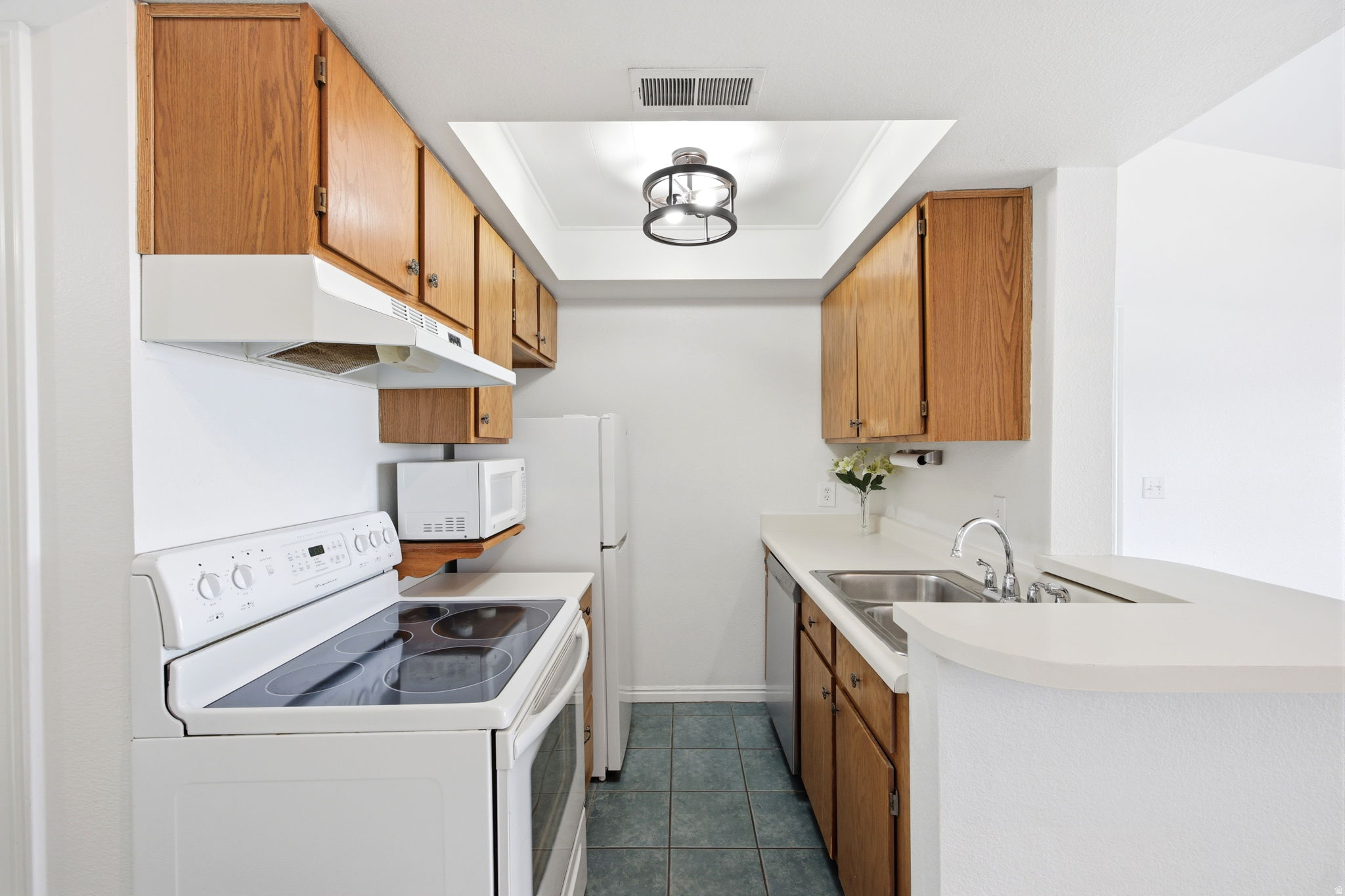 Galley kitchen featuring oak-finish cabinetry, white countertops, and a white electric range
