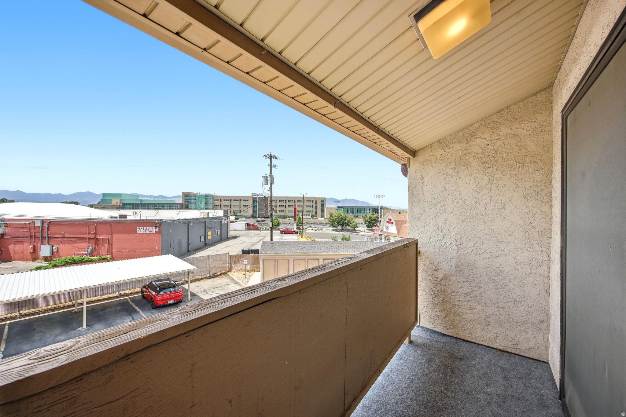 Balcony featuring a partial mountain backdrop, stucco exterior, and a protective railing
