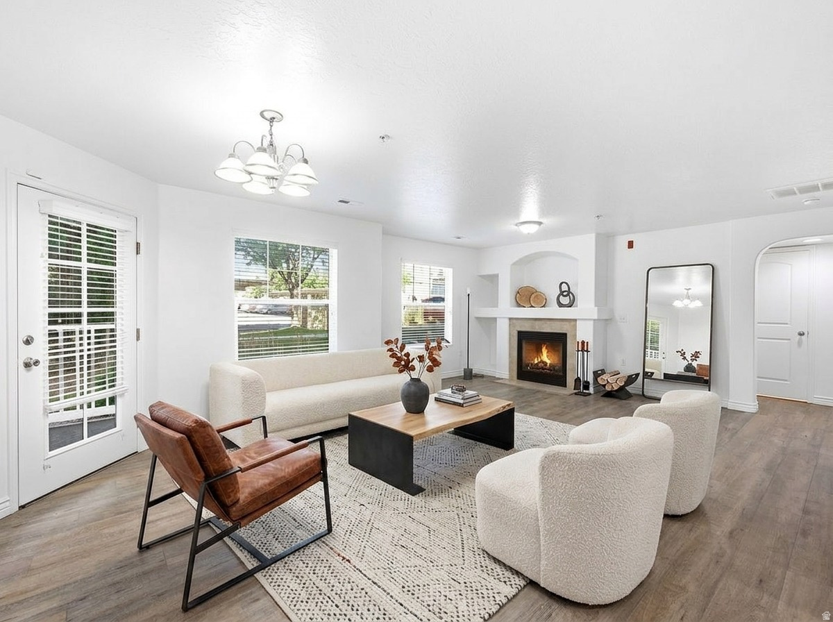 Living space with wood-finish flooring, a fireplace with a stone surround, and an arched entryway