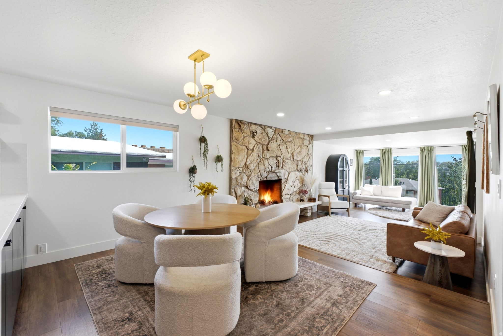 Expansive living area featuring a stone-clad fireplace and wood-finish flooring