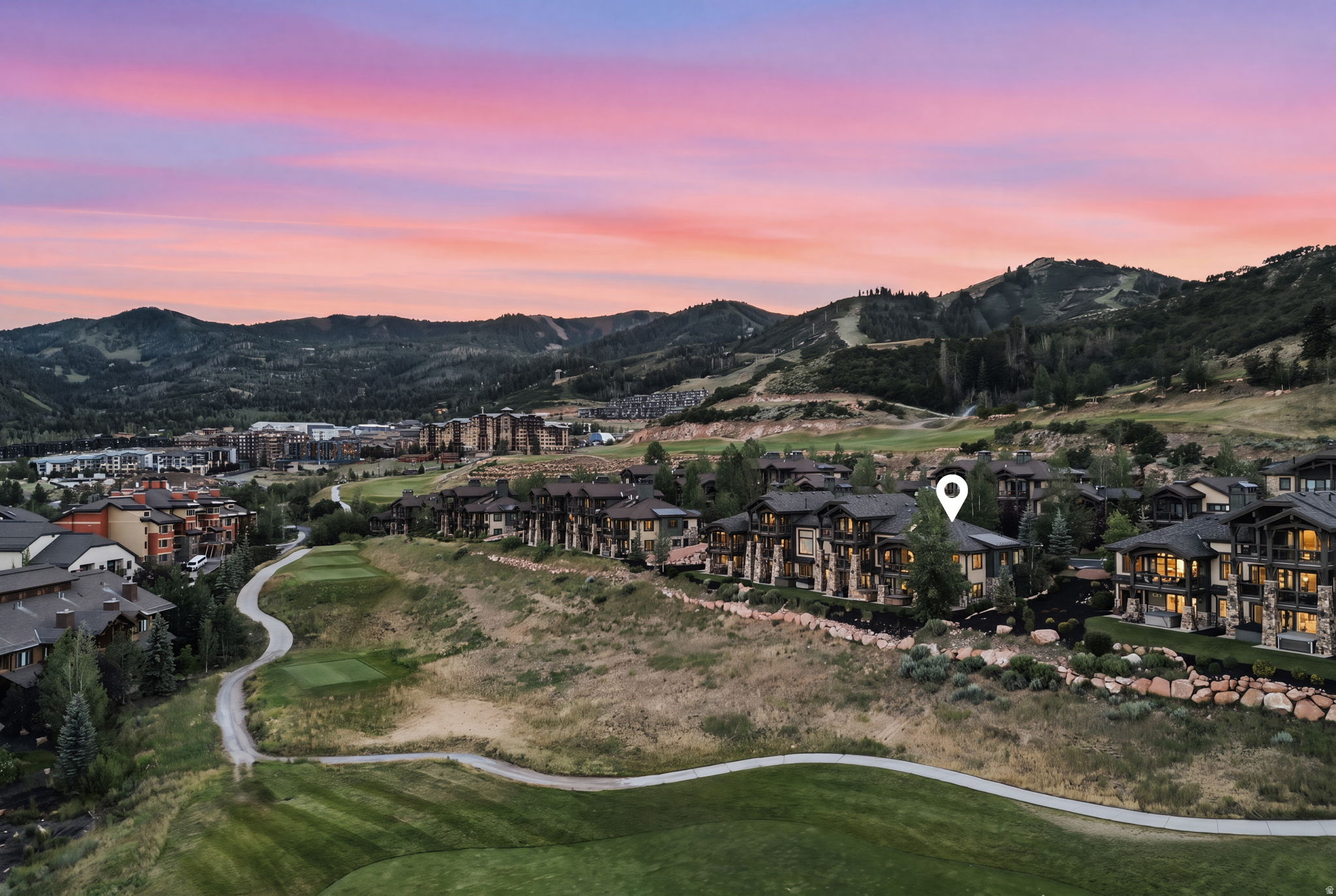 Aerial perspective featuring a residential community amidst a mountainous landscape with a golf course