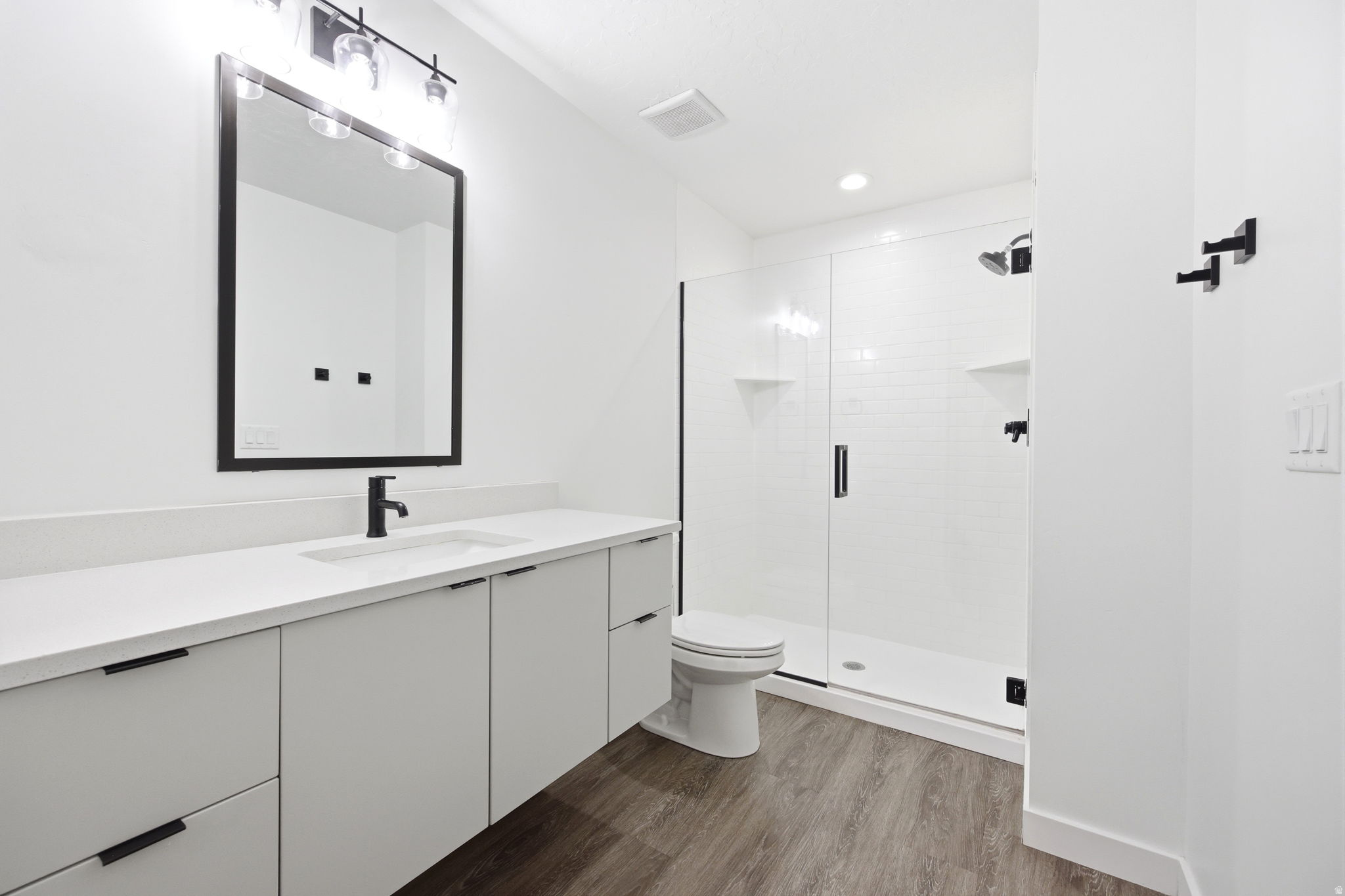 Modern bathroom featuring a spacious vanity with an undermount sink, quartz countertop, and matte black fixtures