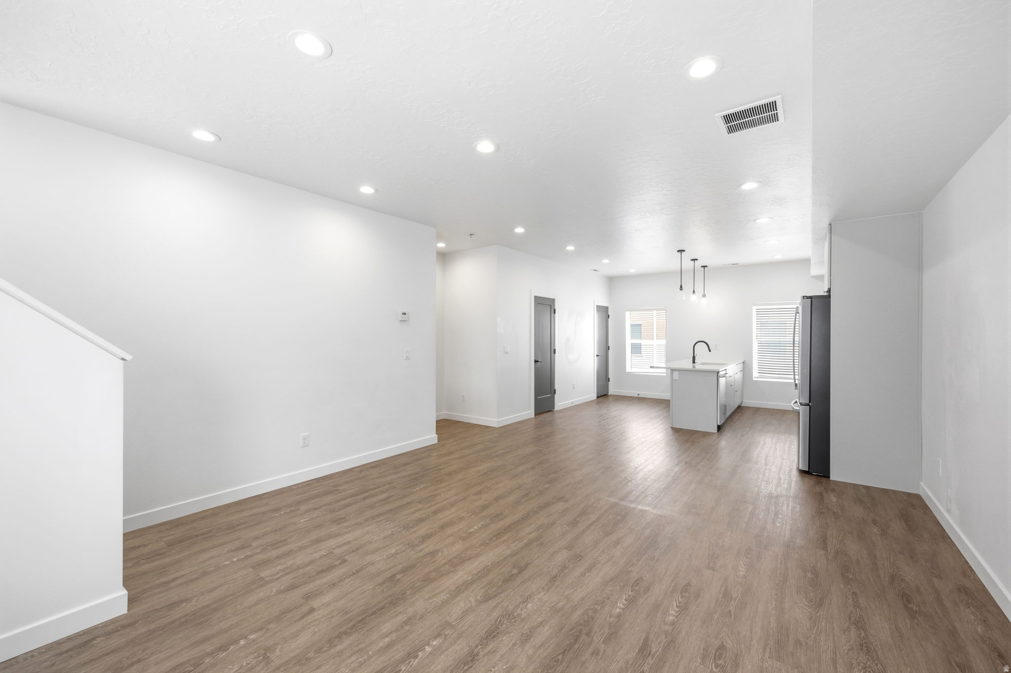 Spacious living area featuring wood-finish flooring, recessed lighting, and a neutral color palette