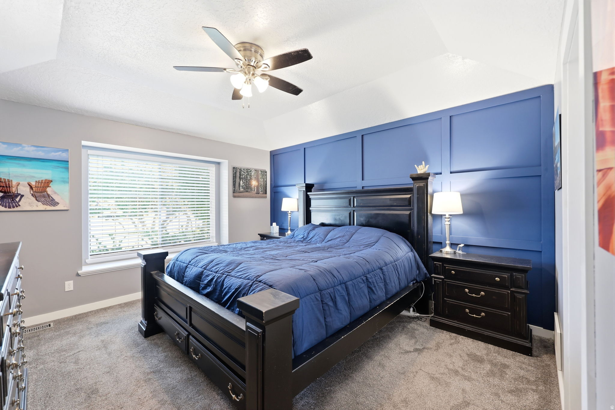 Bedroom featuring a decorative accent wall, vaulted ceiling, and ceiling fan