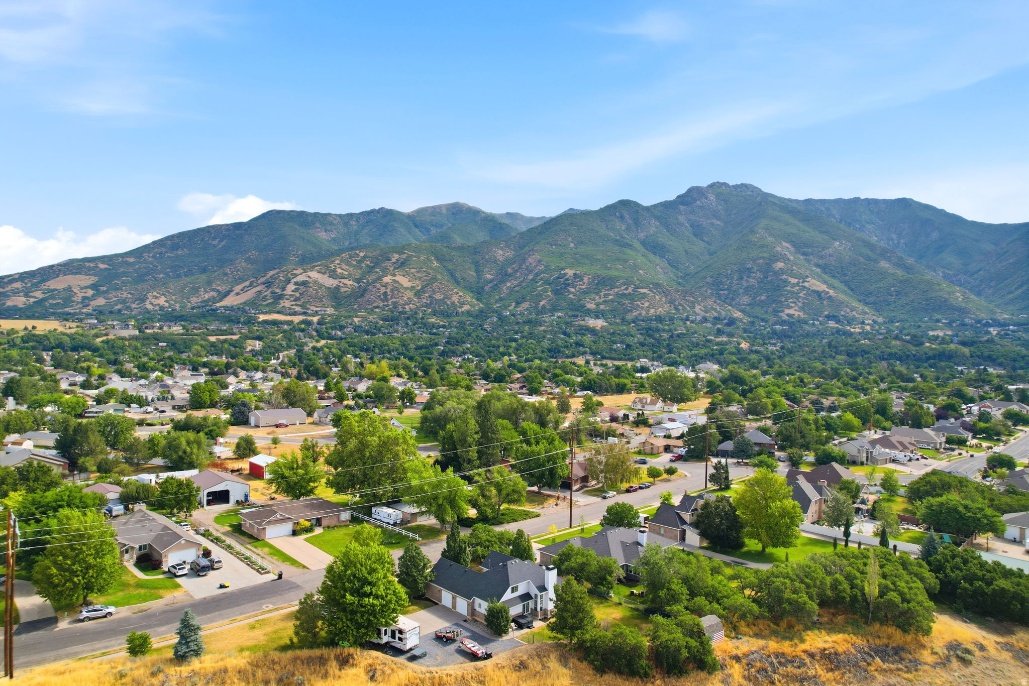 Expansive mountain range backdrop framing a residential area with mature trees and varied architectural styles