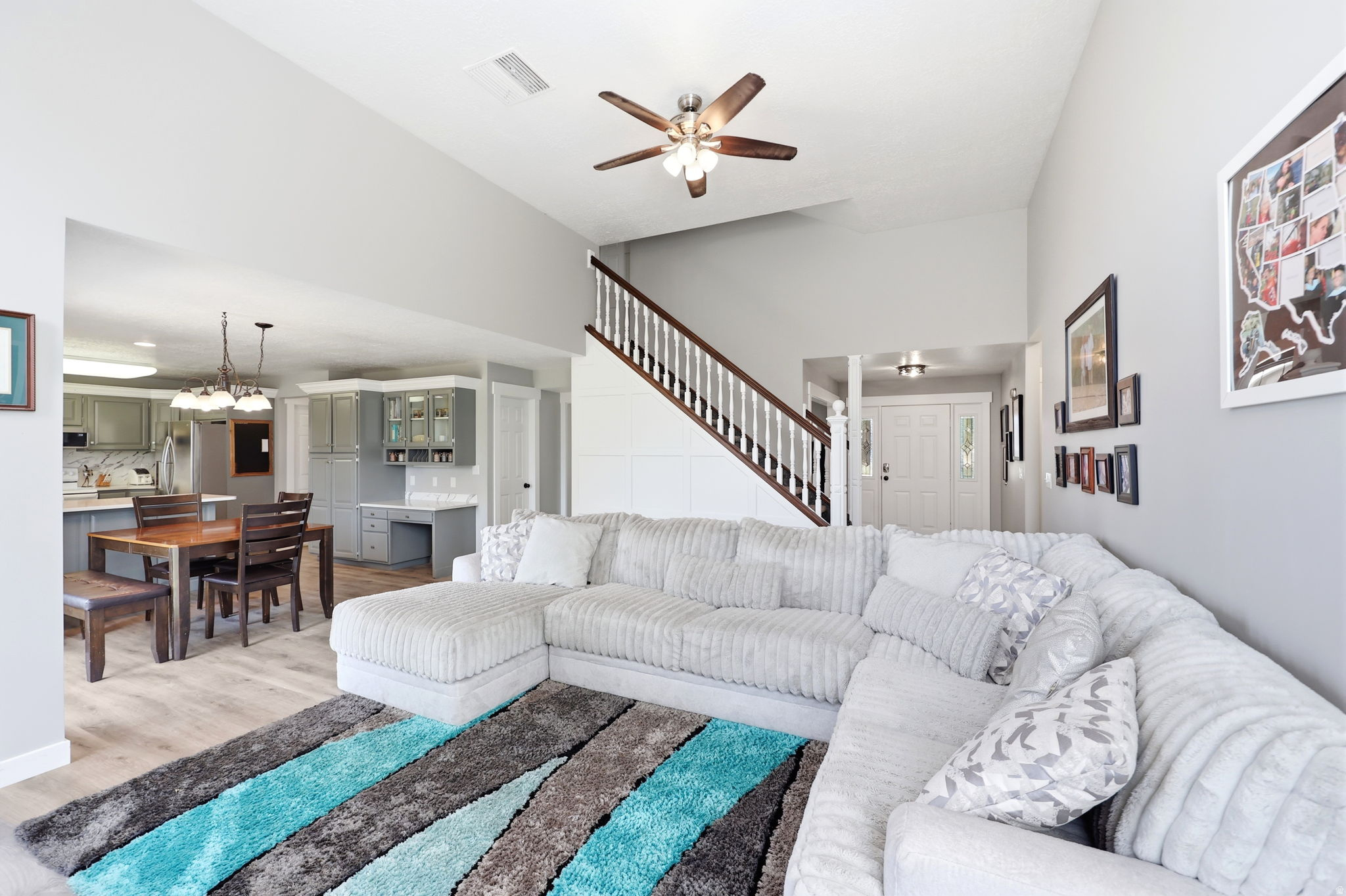 Open-concept living area with wood-finish flooring, vaulted ceilings, and a ceiling fan