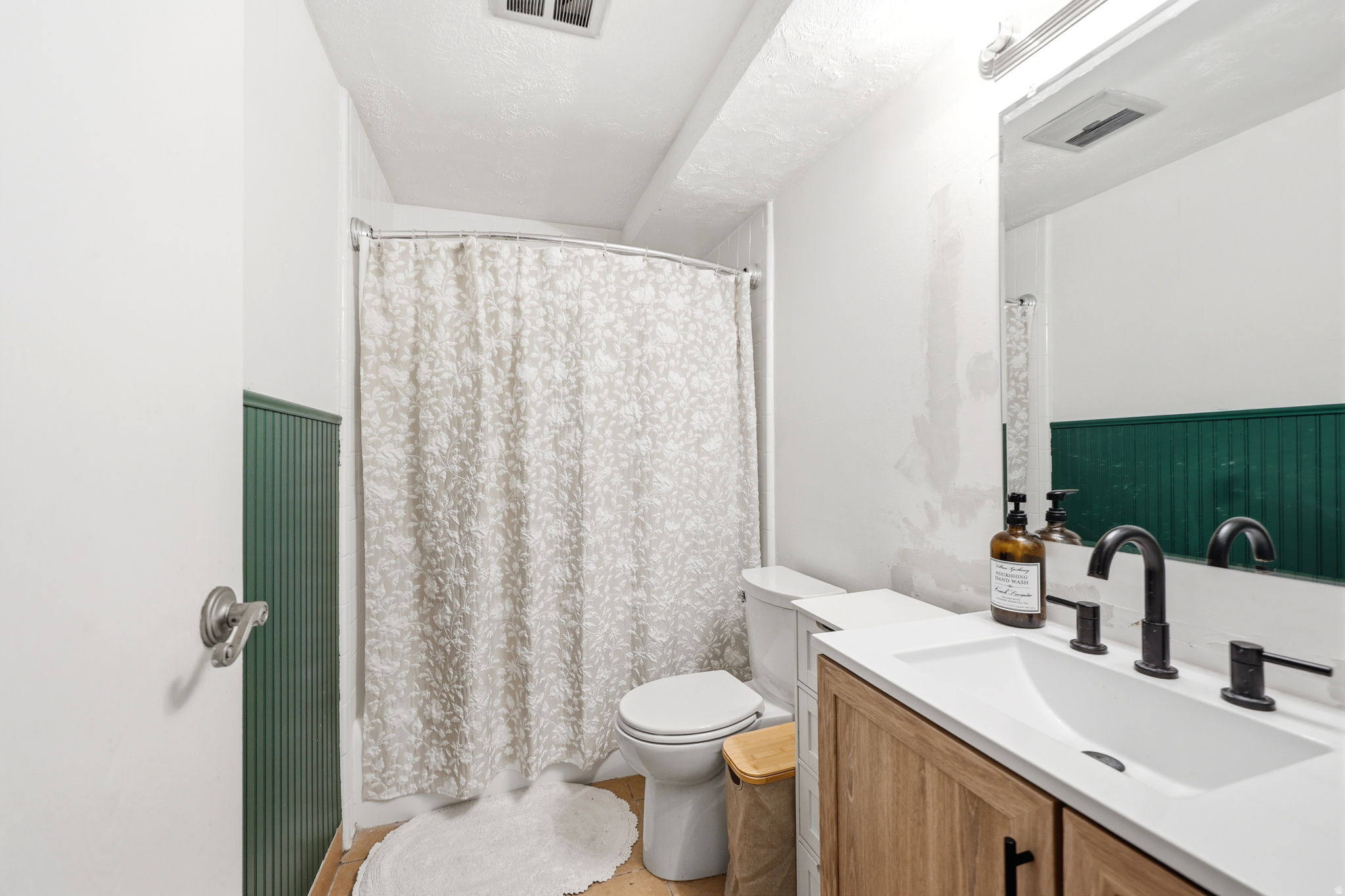 Bathroom featuring a wood-finish vanity with a white countertop and integrated sink, matte black faucet, and a large wall-mounted mirror