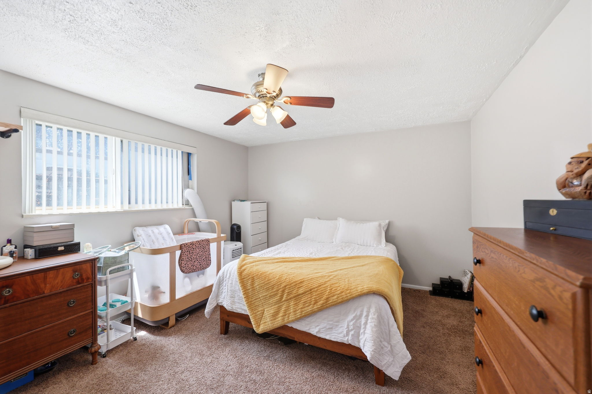 Bedroom featuring a window with vertical blinds, a ceiling fan with integrated lighting, and neutral wall paint