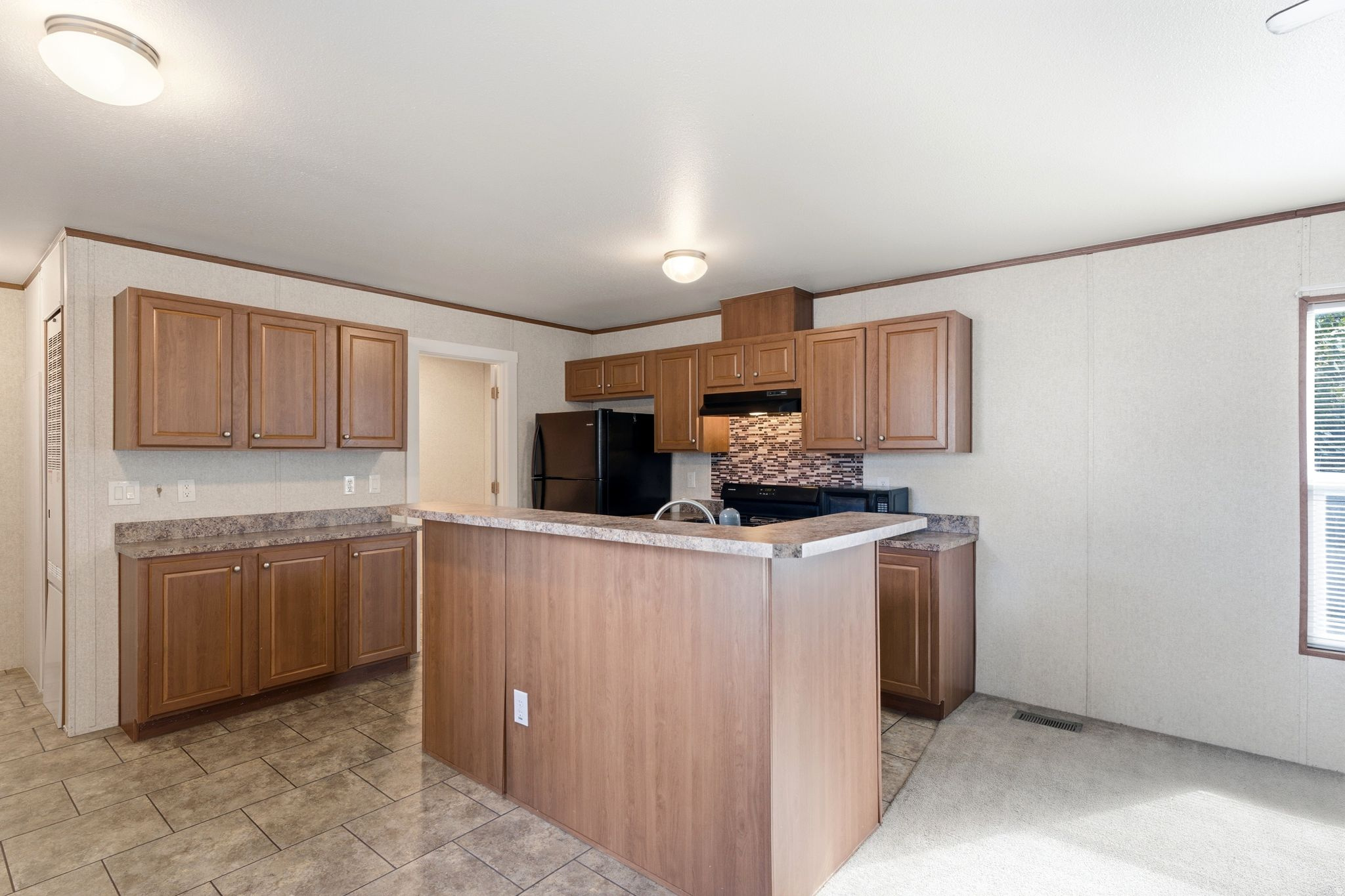 Kitchen featuring wood-finish cabinetry, dark countertops, and a mosaic tile backsplash