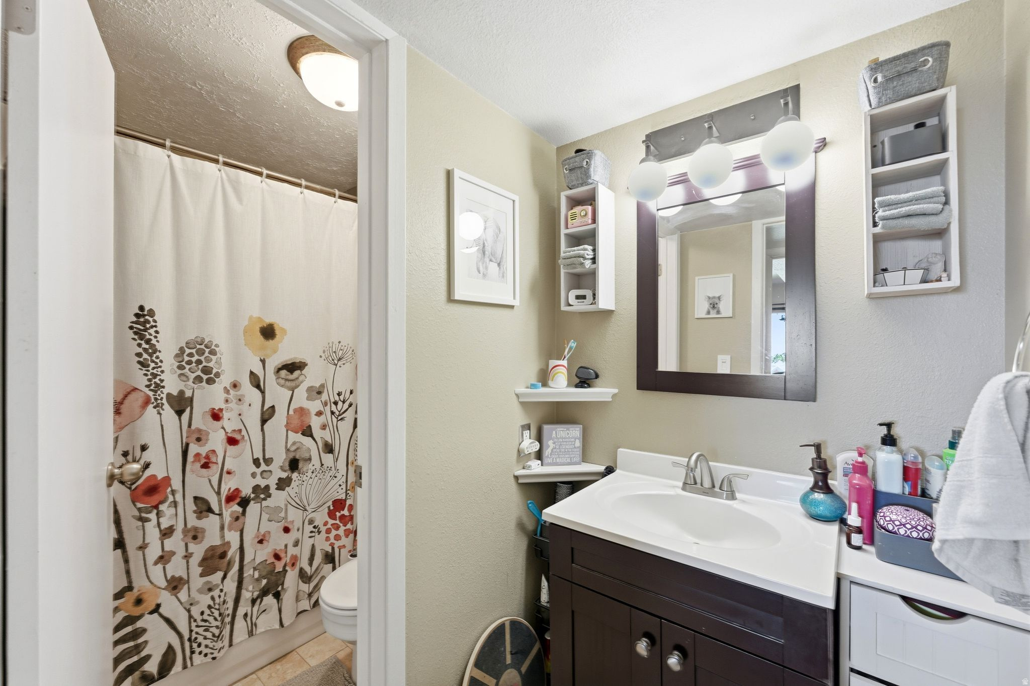 Bathroom featuring a wood-finish vanity with a white countertop and integrated sink, framed mirror, and chrome-finish faucet