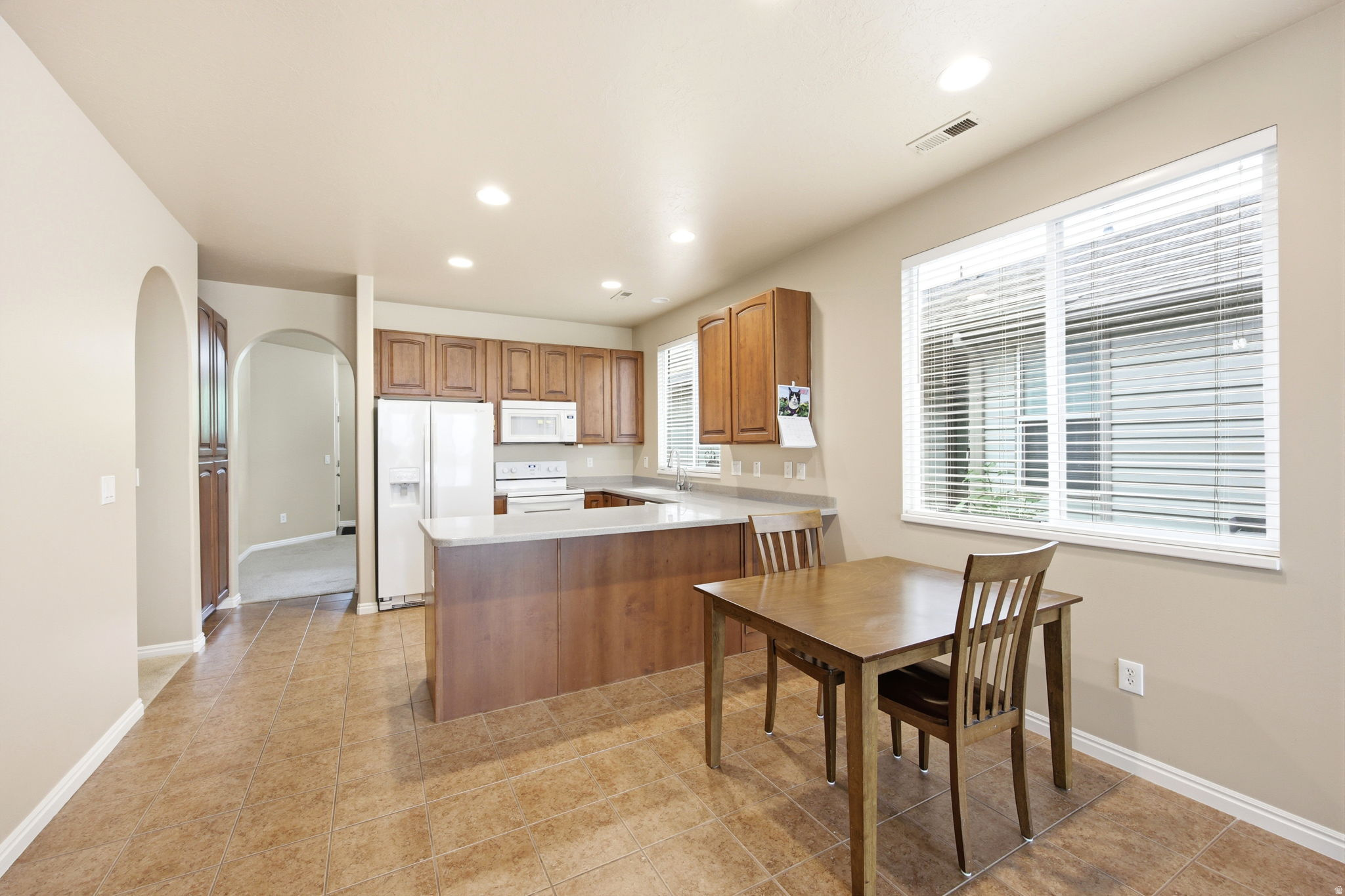 Kitchen featuring wood-finish cabinetry, white appliances, and light-toned countertops