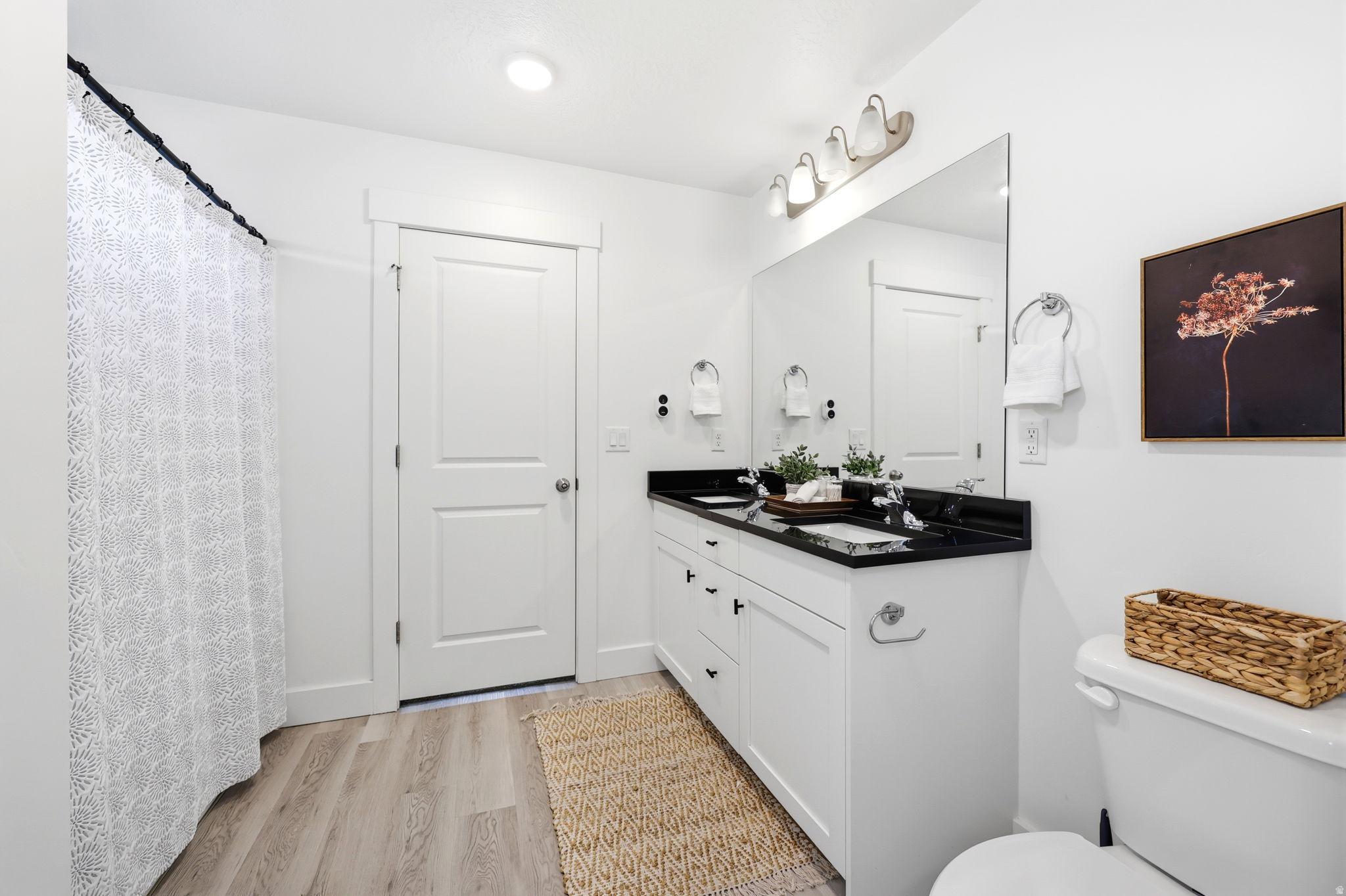 Bathroom featuring a double vanity with black countertops, white cabinetry, and brushed nickel hardware