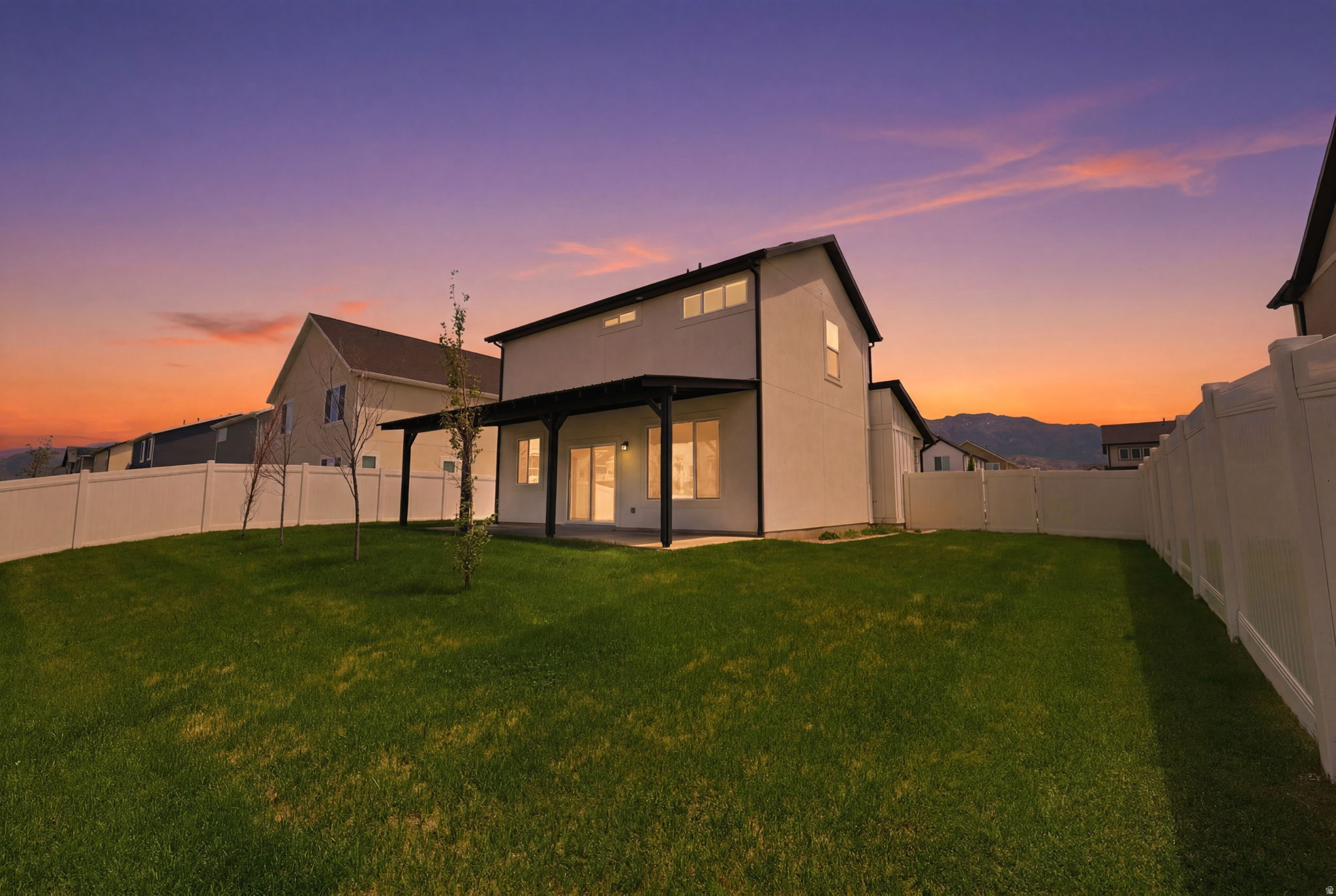 Expansive green lawn with a white vinyl fence enclosing the backyard