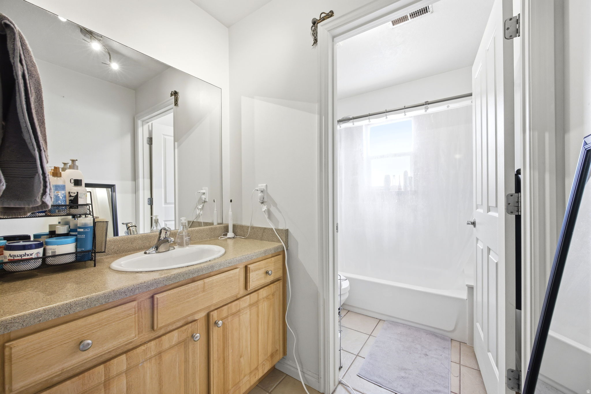 Bathroom vanity featuring wood-finish cabinetry, a white oval sink, and a light-toned countertop