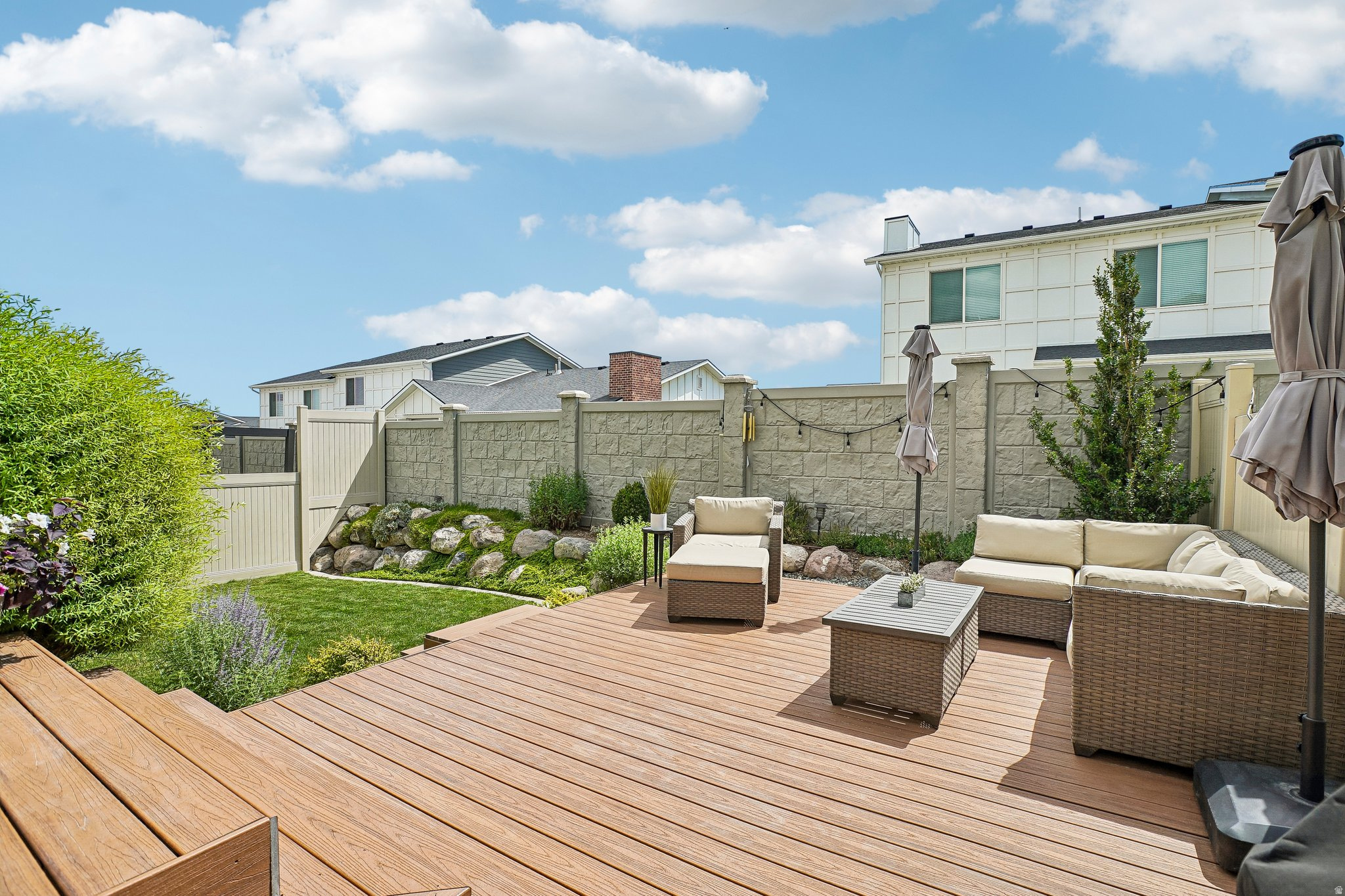 Expansive outdoor decking with a textured finish, bordered by a manicured lawn and garden beds