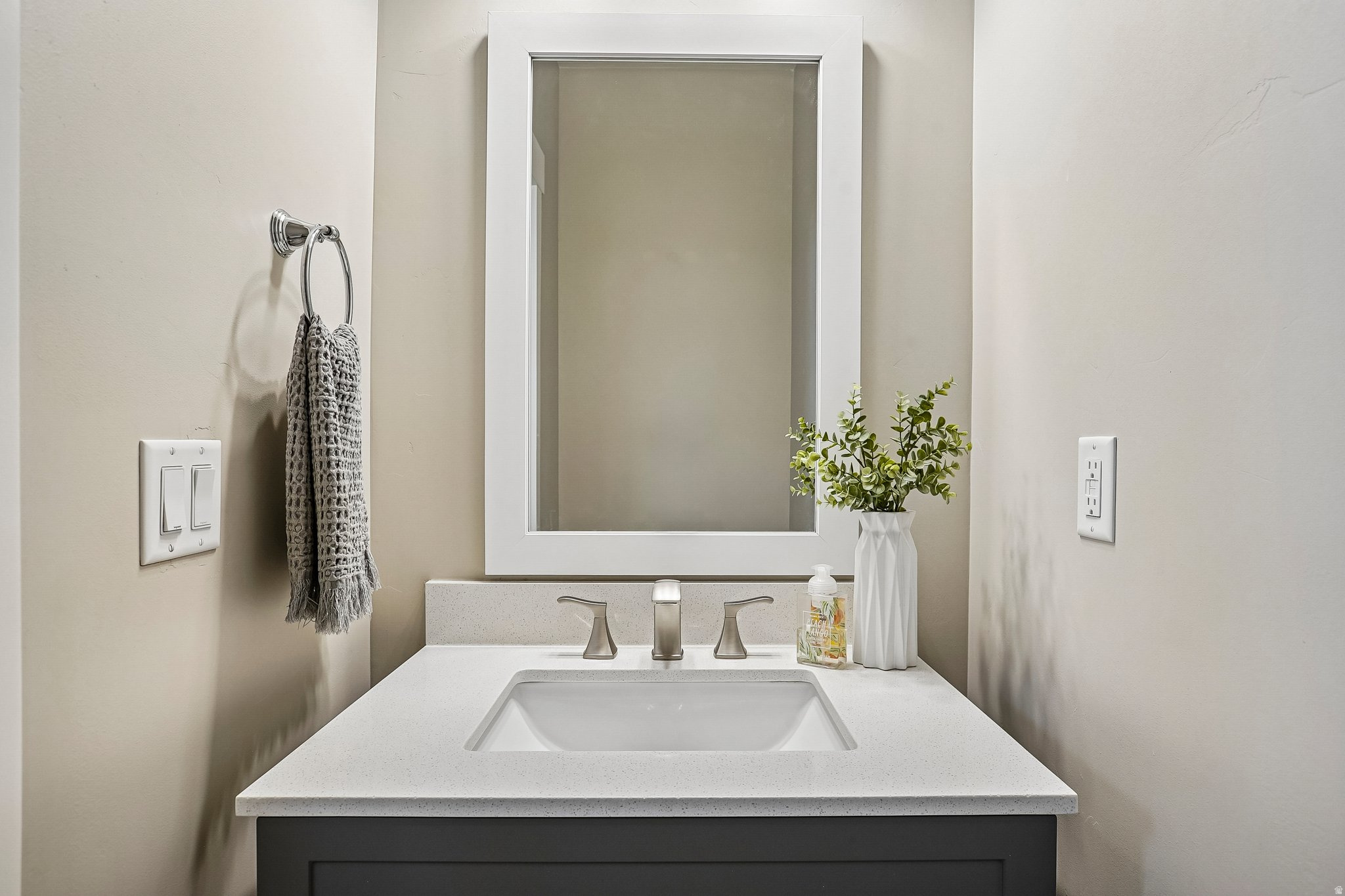 Bathroom vanity featuring a rectangular undermount sink, a light-toned countertop, and a dark-toned cabinet base