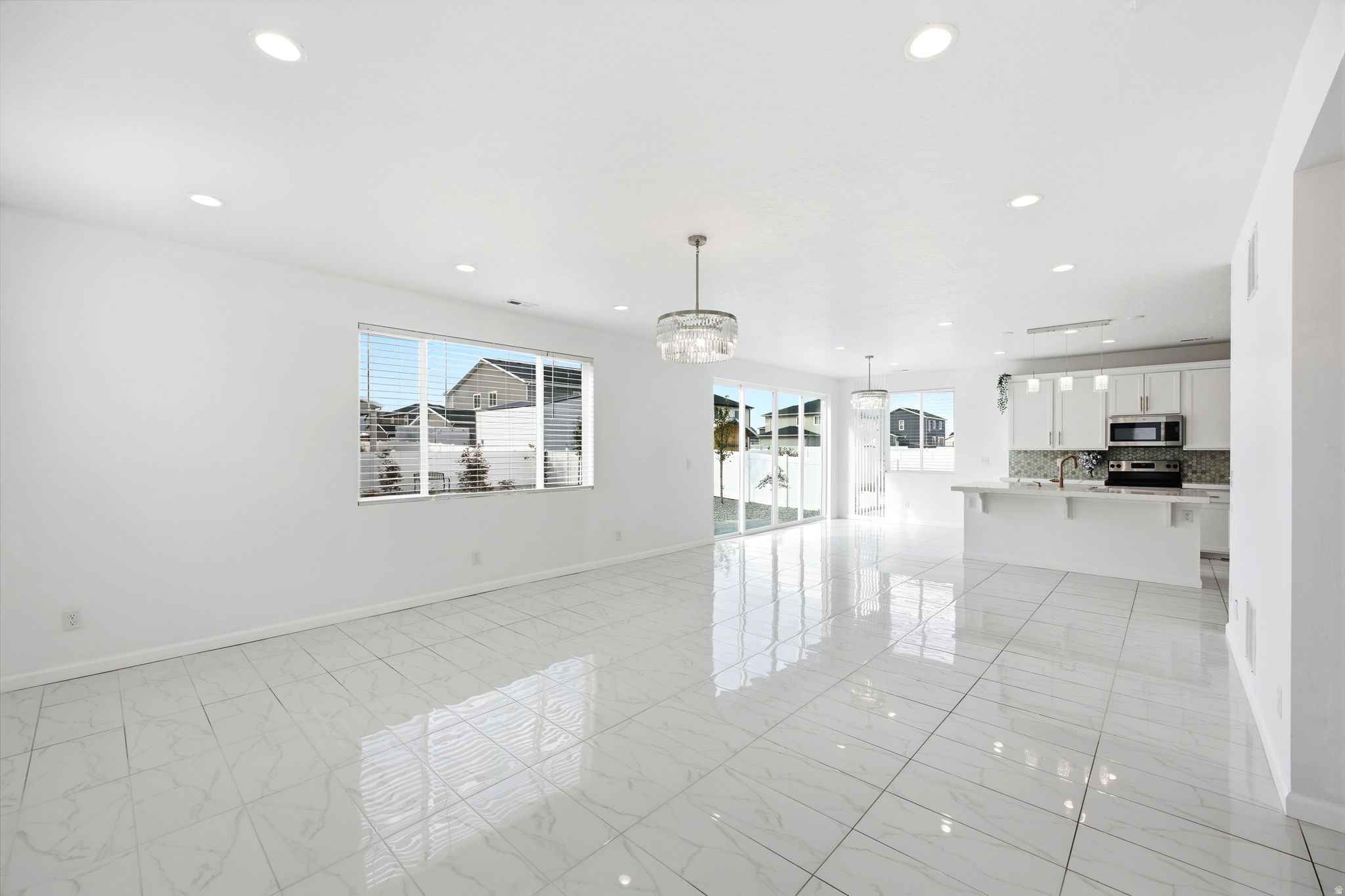 Open-concept living space featuring large format white tile flooring, recessed lighting, and a modern chandelier