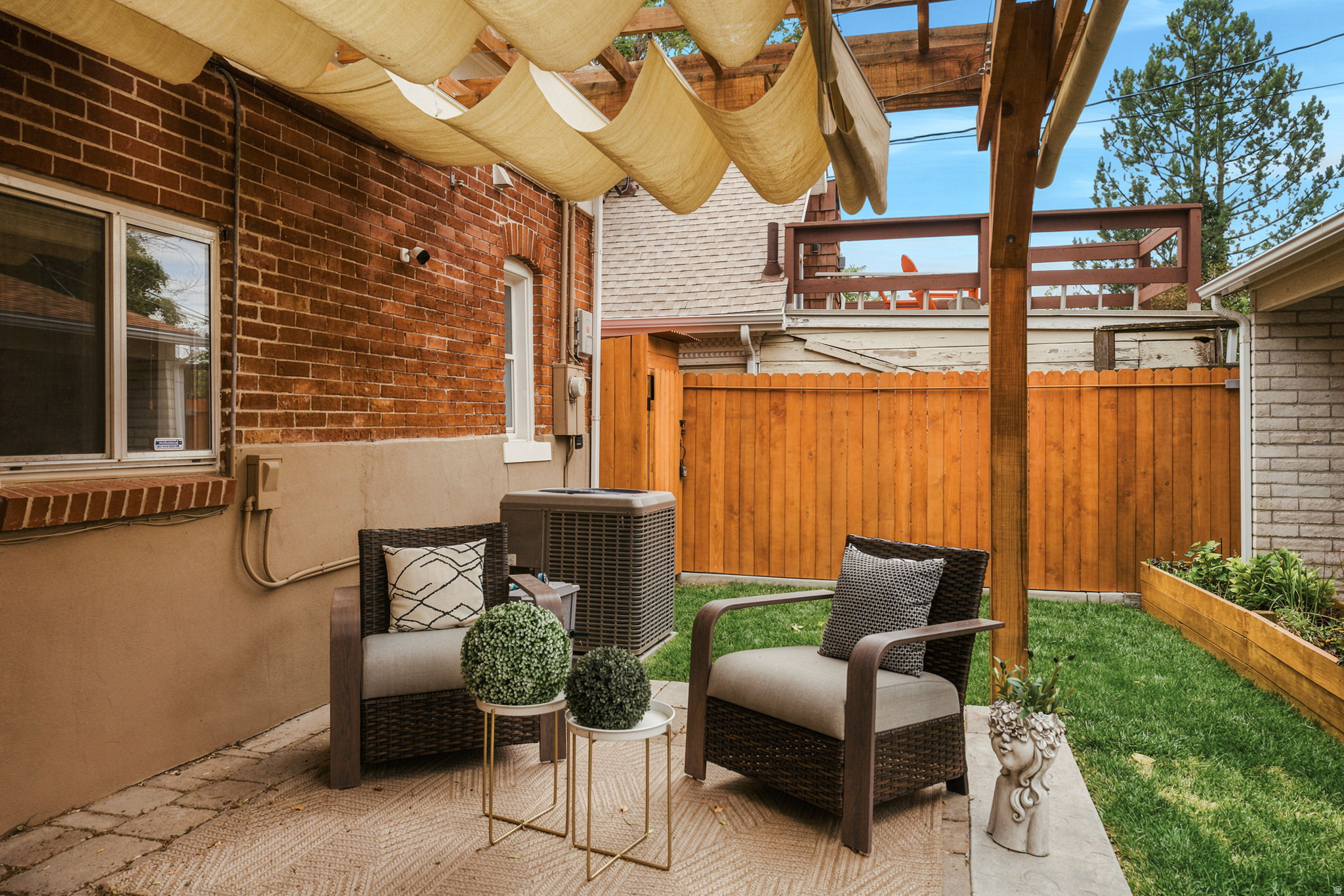 Private patio with a pergola featuring a retractable shade canopy, brick exterior, and a manicured lawn