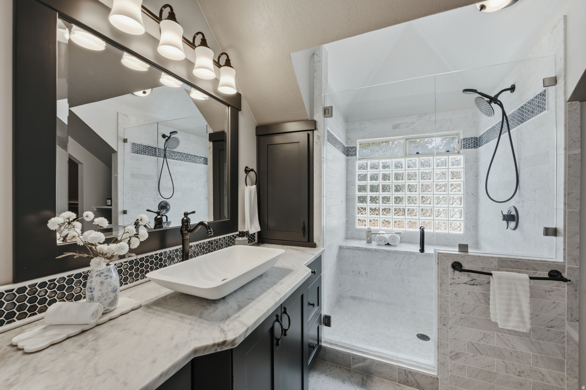 Bathroom featuring a glass-enclosed shower with a glass block window