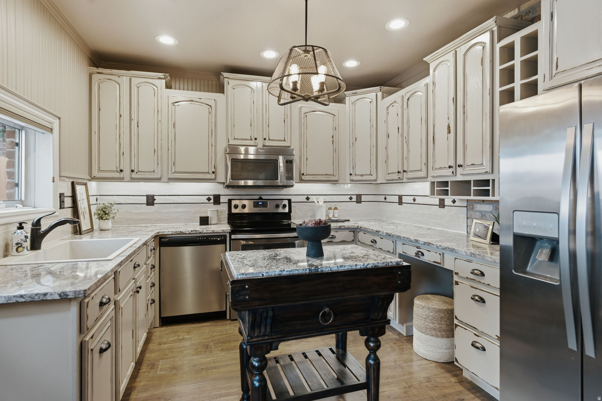 Kitchen featuring distressed white cabinetry, light-toned countertops, and stainless steel appliances