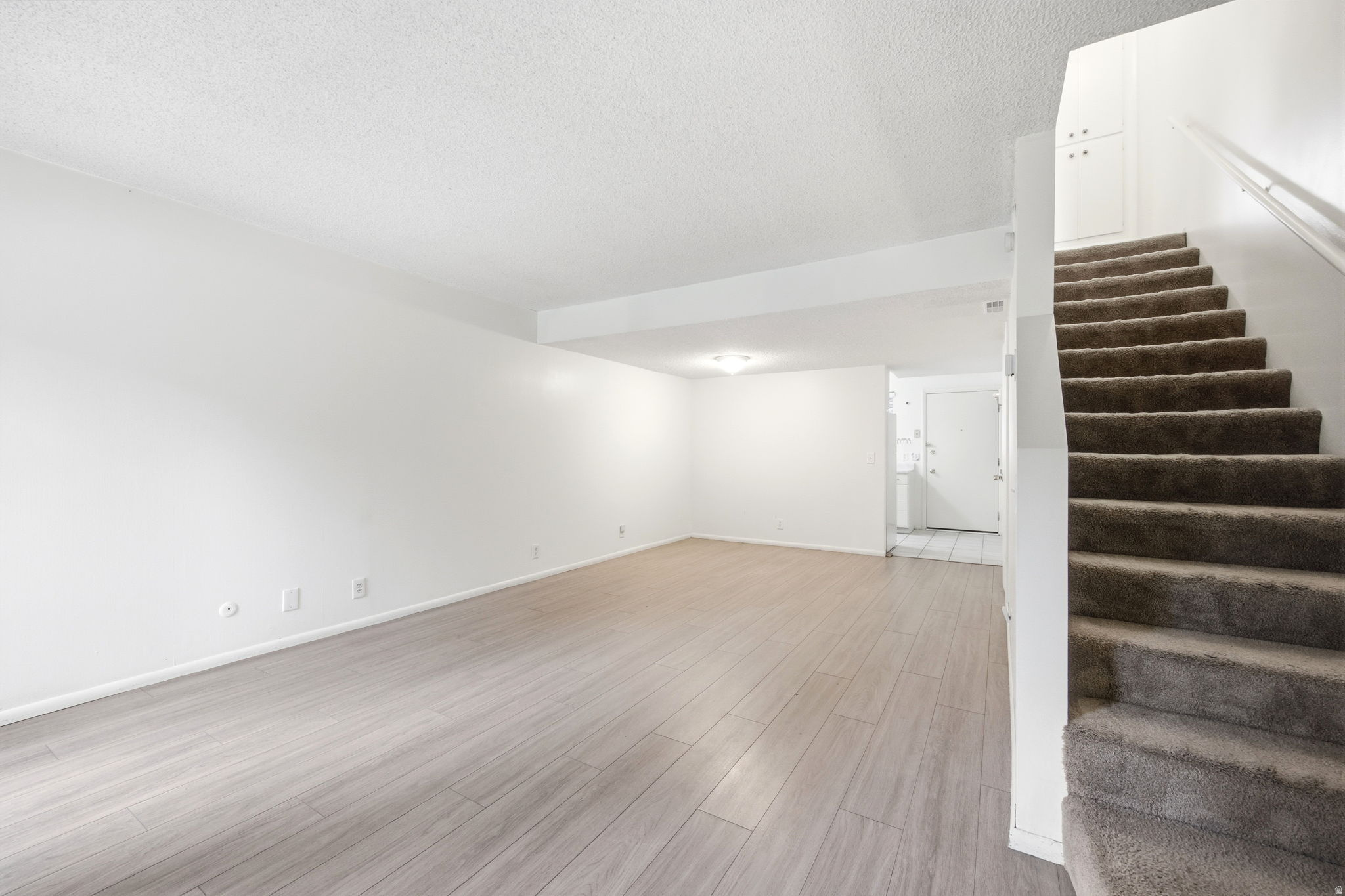 Spacious living area featuring light wood-finish flooring and a neutral color palette