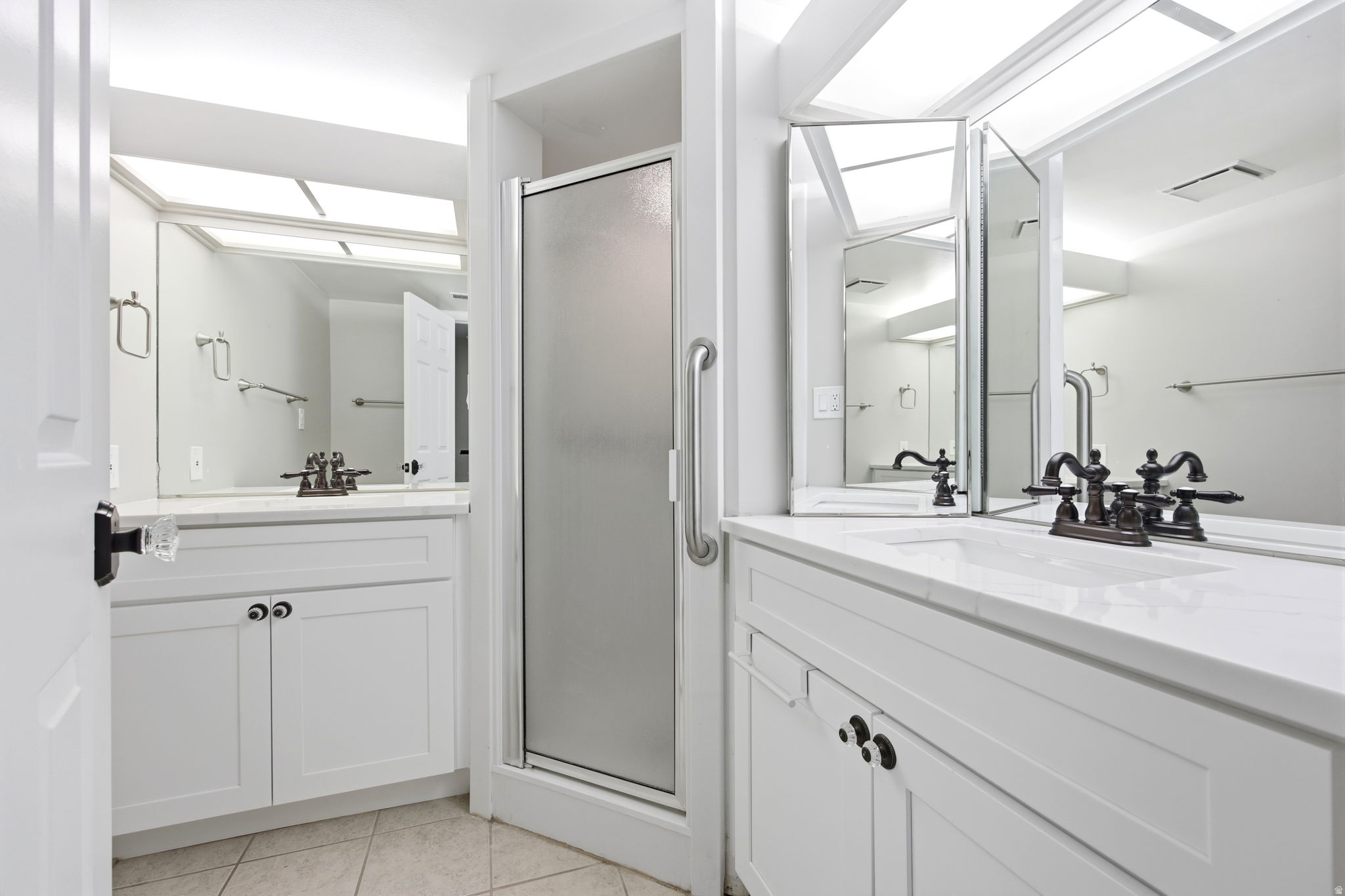 The bedroom has a private bath. Twin vanity setup featuring white cabinetry, integrated sinks, and bronze-finish faucets