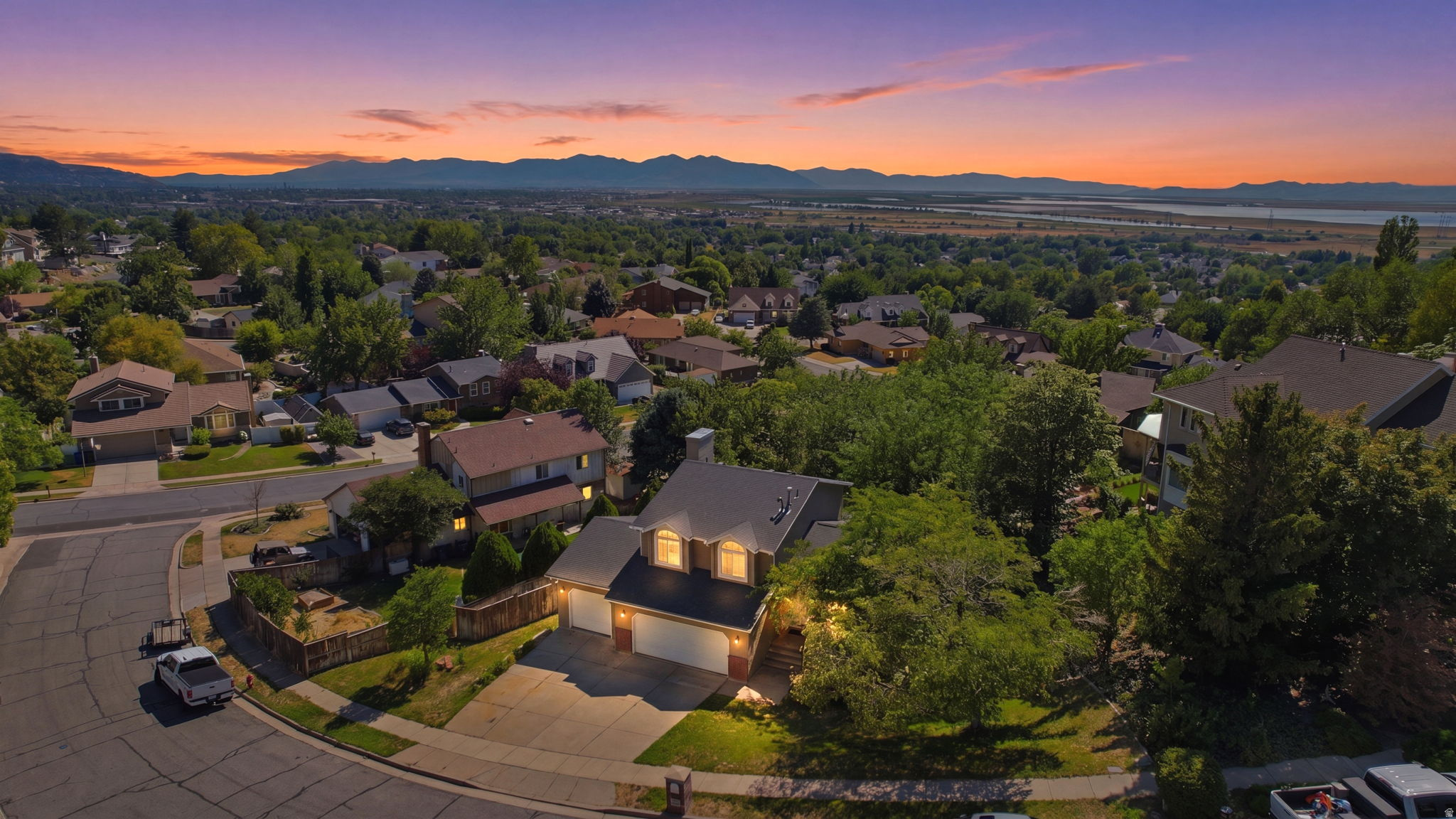 Suburban home featuring a two-car garage, established landscaping, and a fenced yard