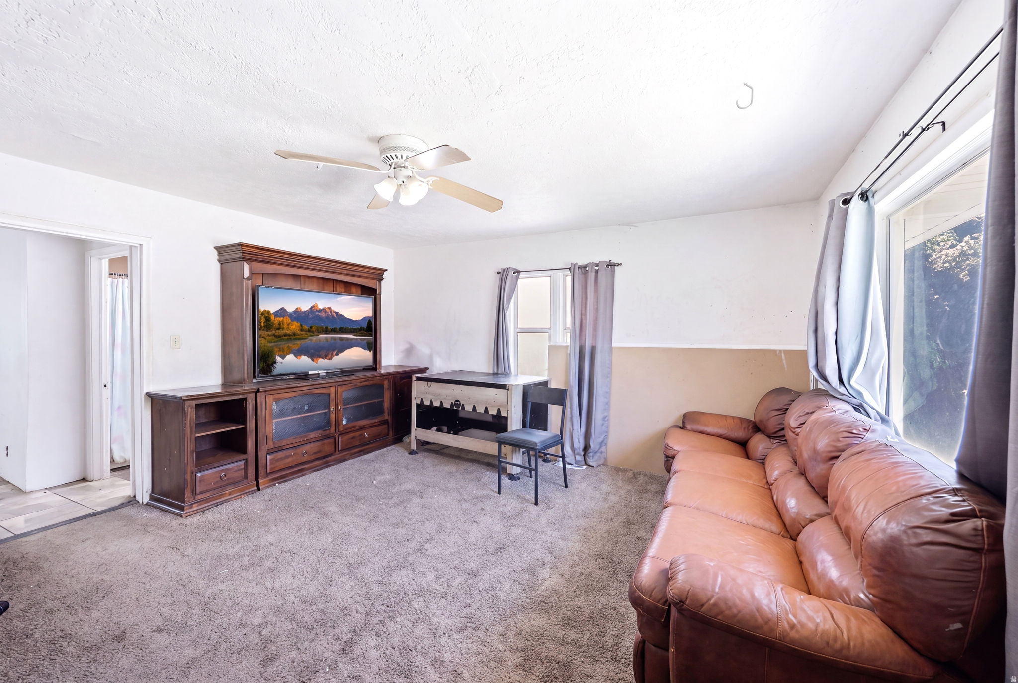 Living area featuring a ceiling fan with light fixture, built-in entertainment center with storage, and natural light from multiple windows