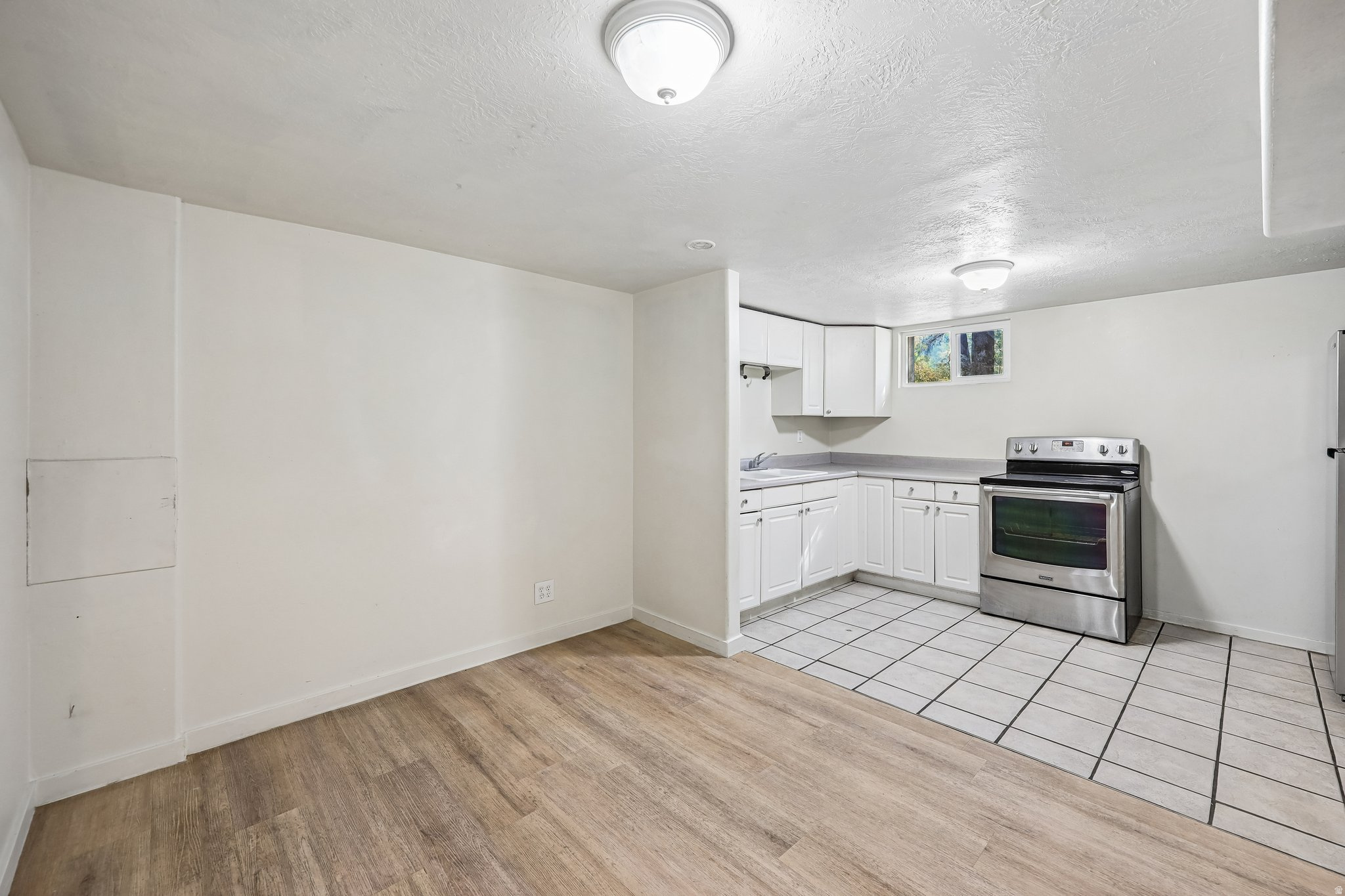 Compact kitchen featuring white cabinetry, a stainless steel range, and tile flooring