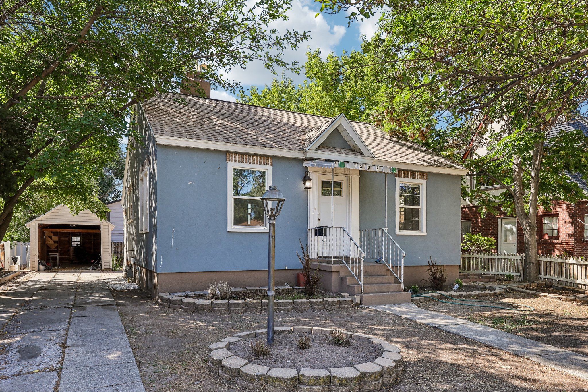 Blue stucco exterior with white trim, covered front porch, and a detached two-car garage