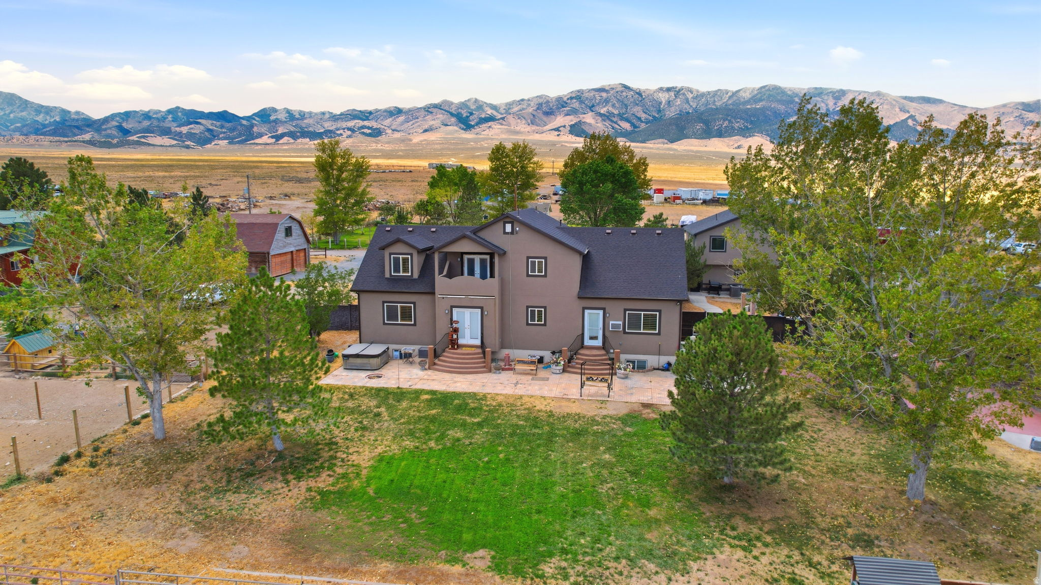 Expansive backyard featuring a manicured lawn, mature trees, and a mountain backdrop