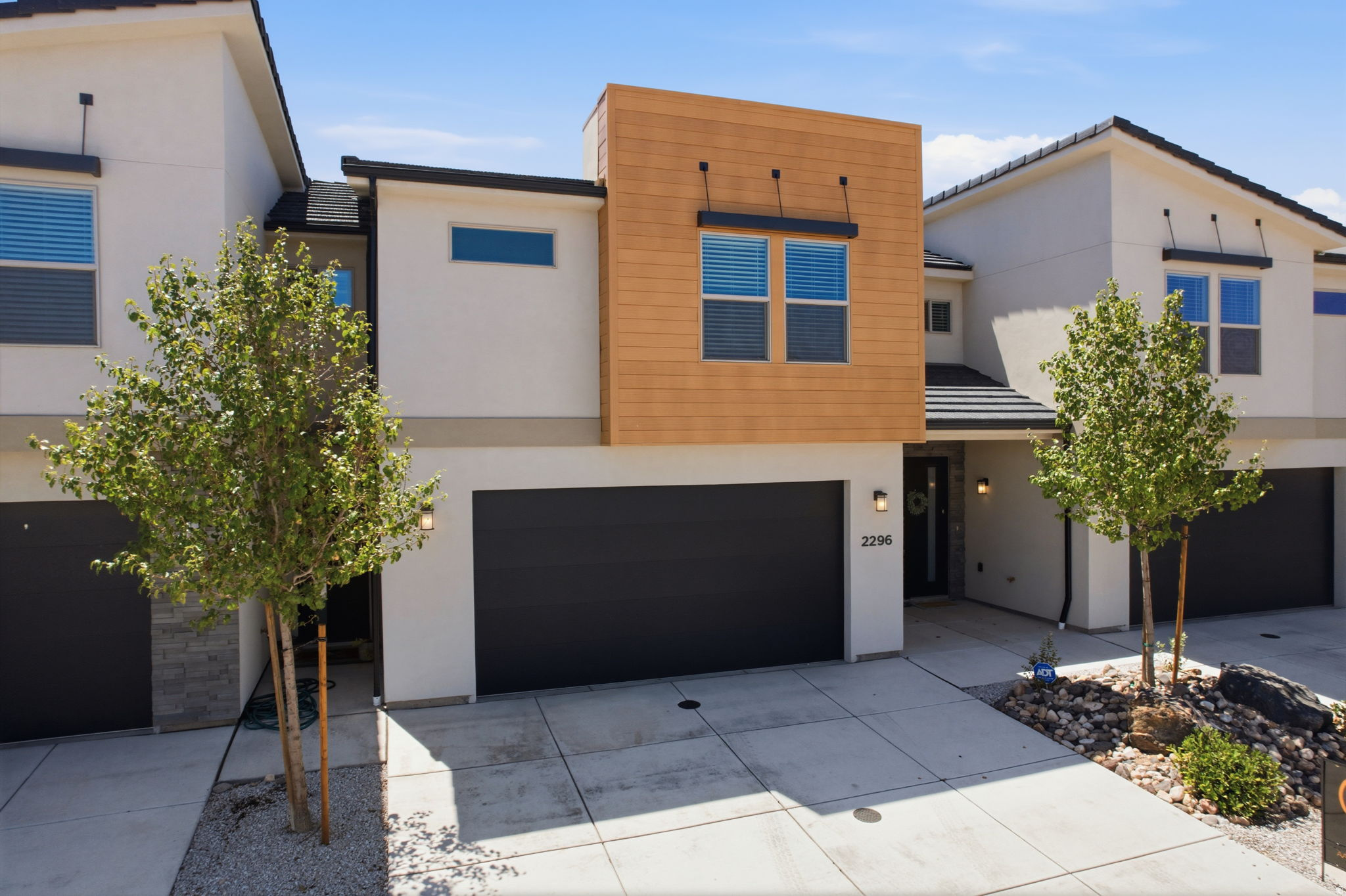 Modern townhome exterior featuring a wood-look facade accent, stucco siding, and a two-car garage