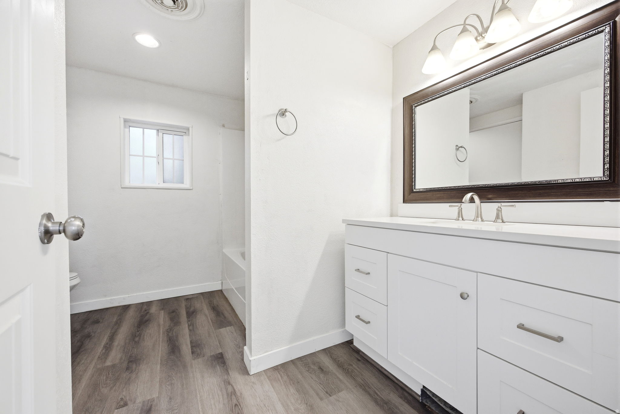 Bright bathroom featuring a contemporary vanity with white cabinetry, a light-toned countertop, and a large framed mirror