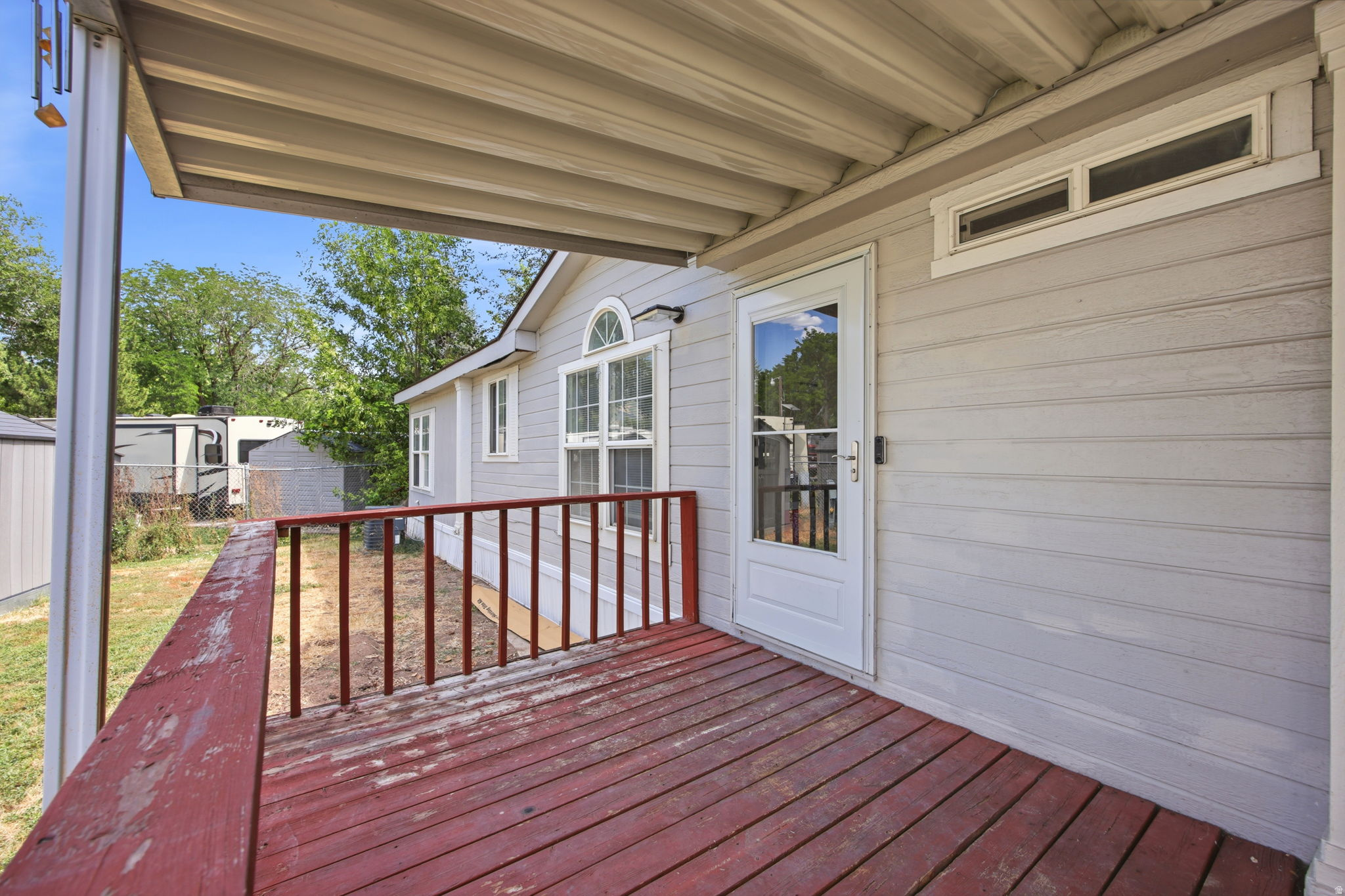 Covered porch featuring wood flooring and red railings