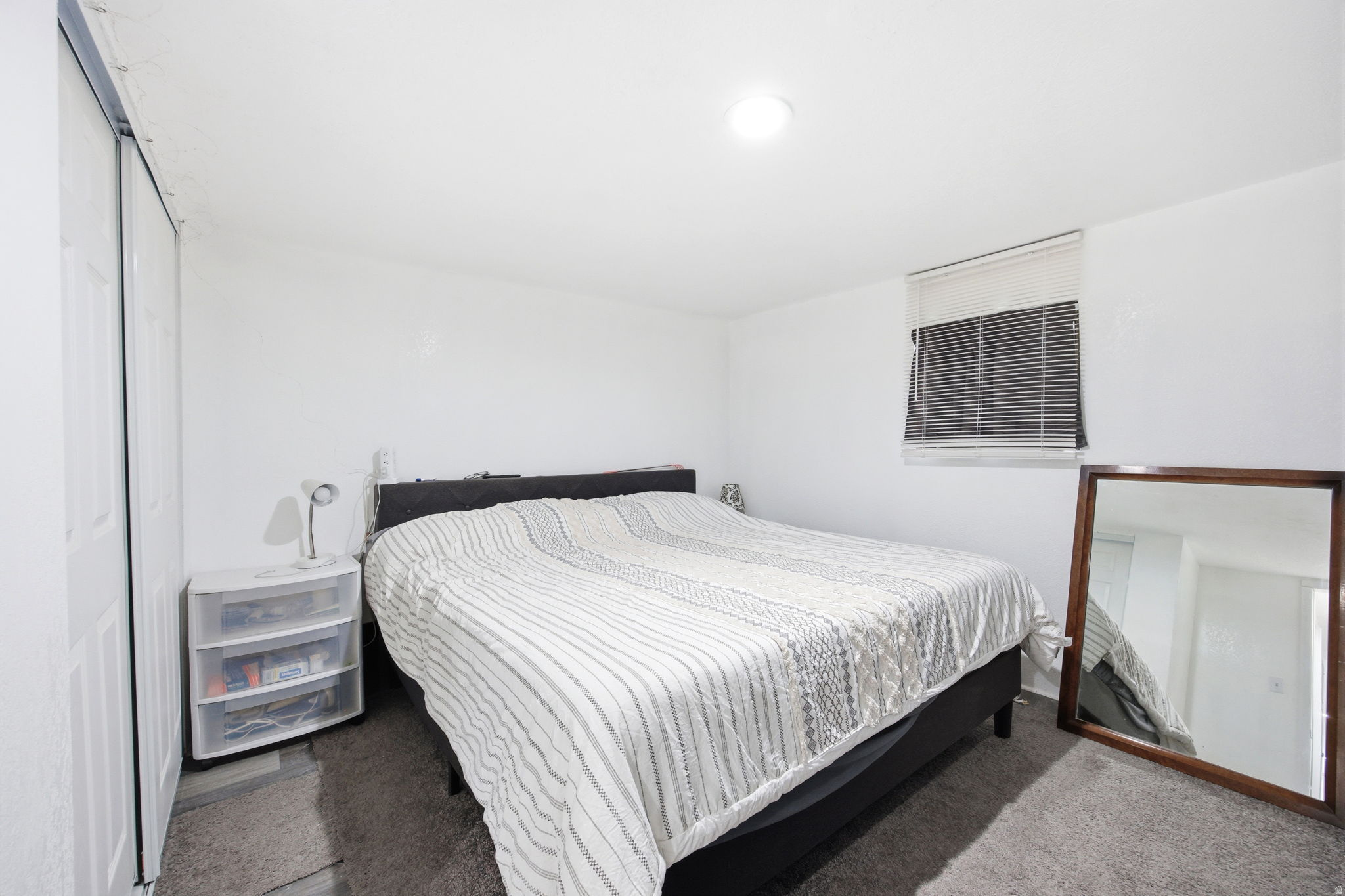 Bedroom featuring a window with horizontal blinds, overhead lighting, and wall-to-wall carpeting