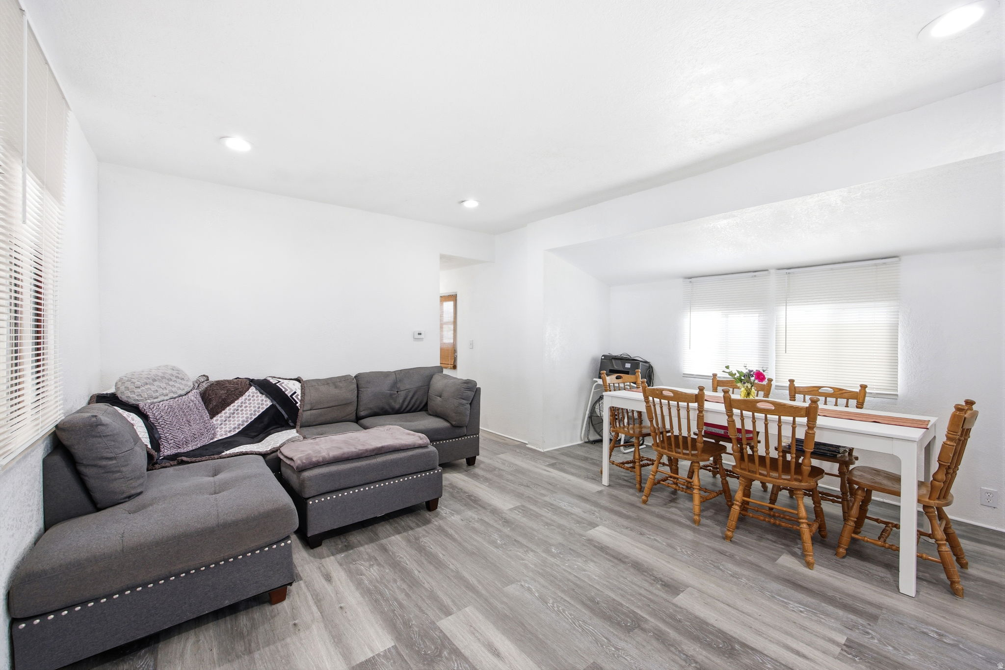 Open-concept living space featuring wood-finish flooring, recessed lighting, and white walls