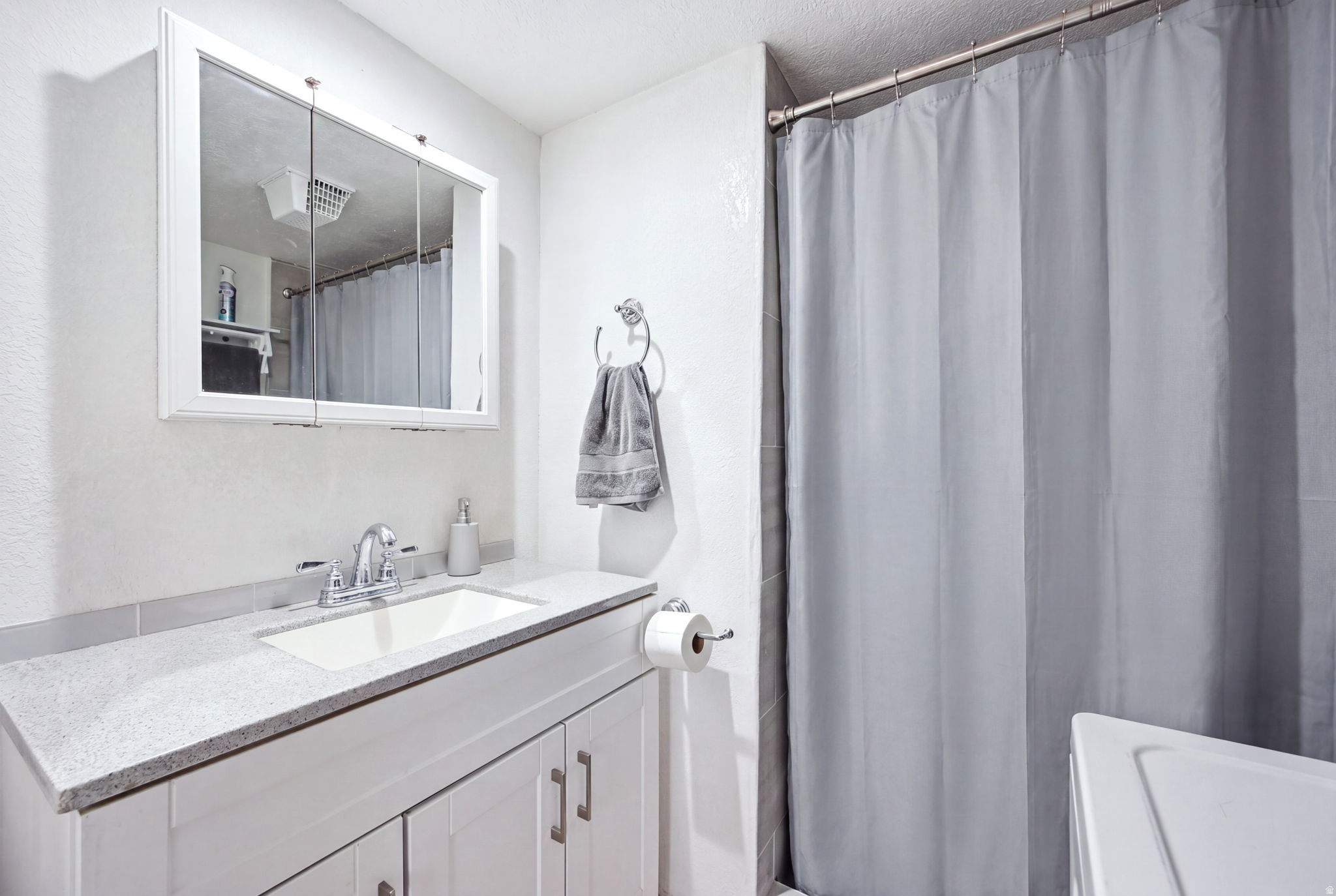 Bathroom featuring a white vanity with a light-colored countertop, an undermount sink, and a chrome faucet