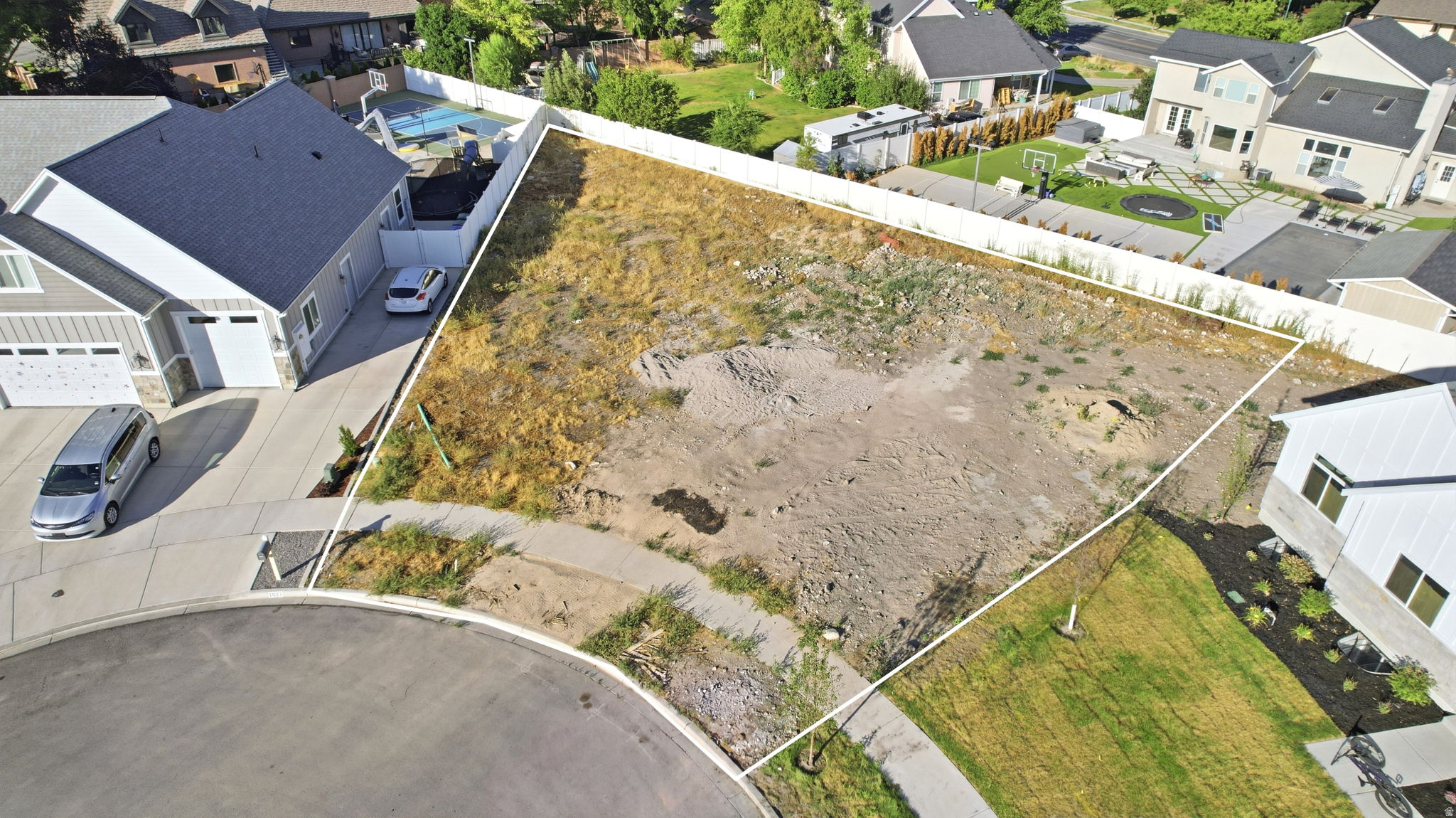 Vacant lot featuring a level building area and a partial white privacy fence