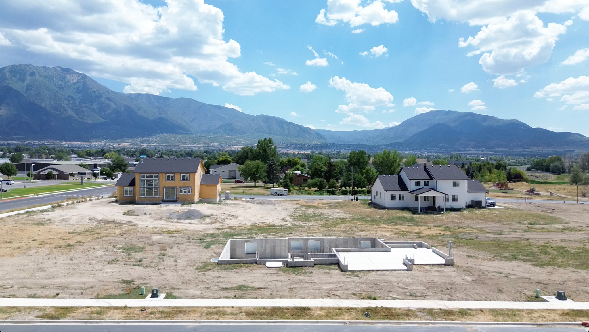 Mountain backdrop with a partially constructed home and a concrete foundation on a spacious lot